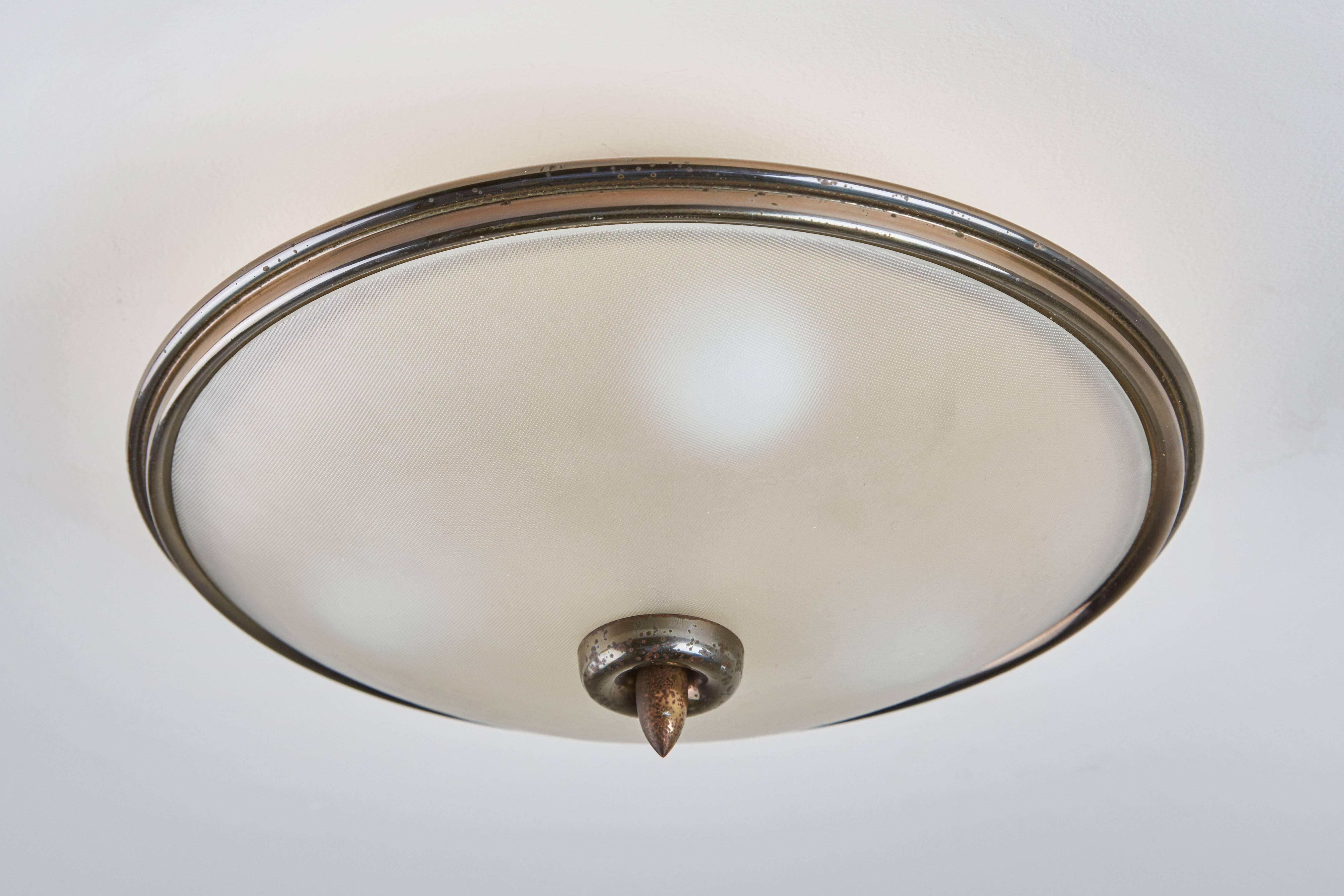 Pair of brass and textured glass Italian flush mount ceiling lights designed in Italy, circa 1950s. Rewired for US junction boxes. Takes three E27 75w maximum bulbs per light.

Pair of larger size available.