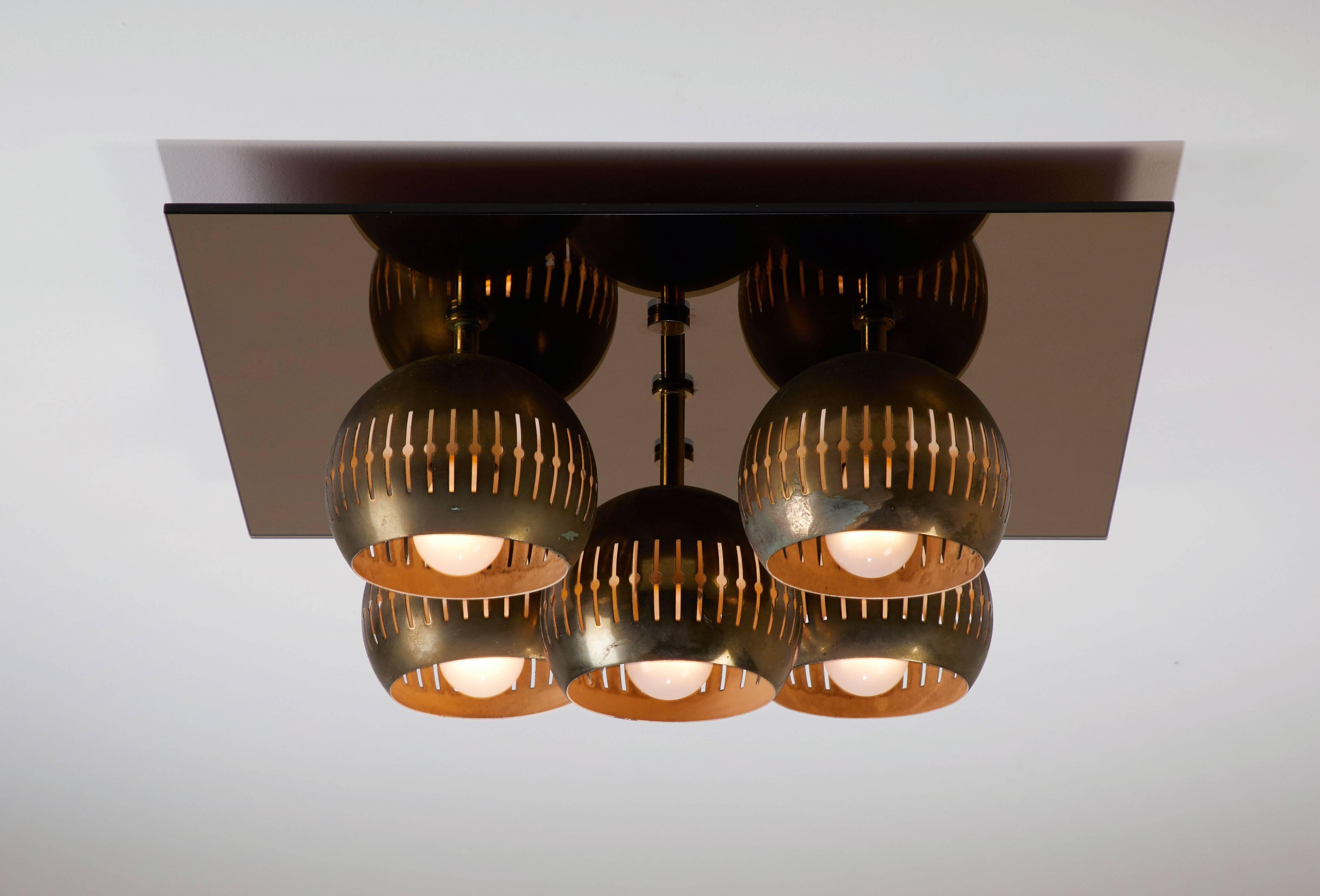 Five-shade flush mount ceiling light by Angelo Lelli for Arredoluce manufactured in Italy, circa 1960s. Mirror glass base and five perforated brass diffusers. Wired for US junction boxes. Each socket takes one E27 40w maximum bulb. Original