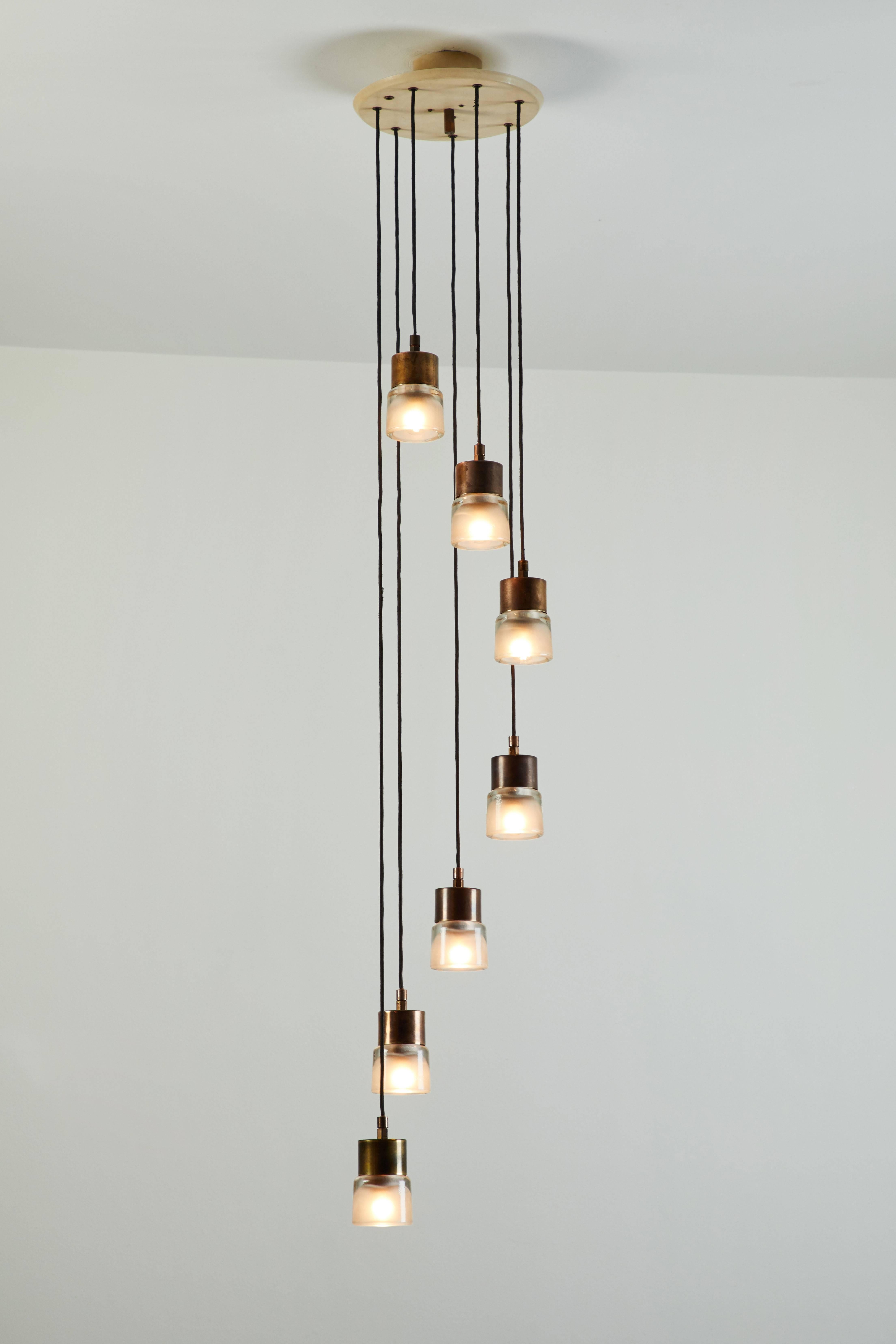 Original nine shade cascading chandelier designed by Tito Agnoli for Oluce in Italy, circa 1950s. Painted aluminum, brass and pressed glass. Wired for US junction boxes. Each socket takes an E14 European candelabra 25w maximum bulb.