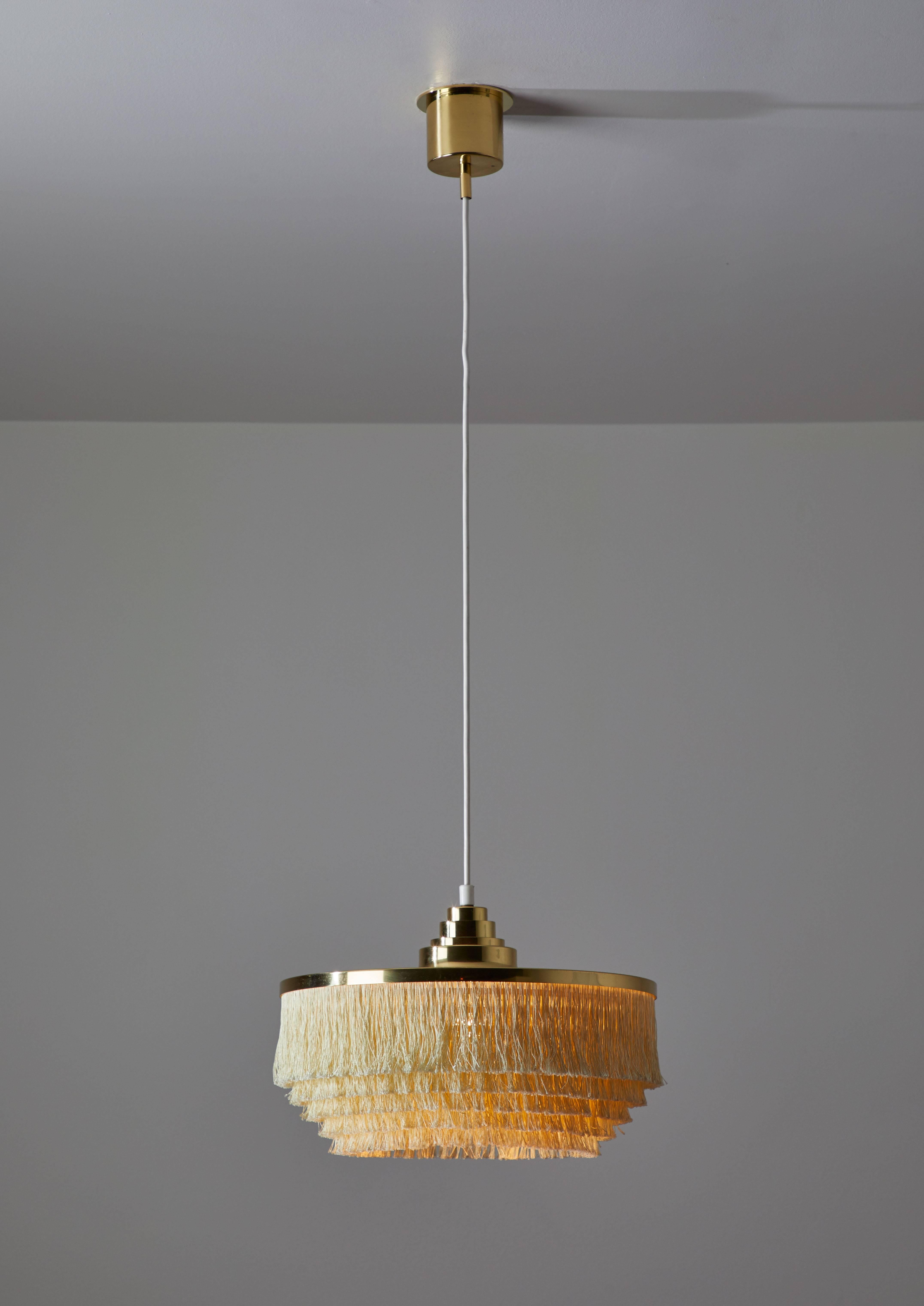 One fringe silk cord pendant by Hans Agne Jakobsson, Markaryd. Five tiers of cream colored fringe silk cord with brass hardware frame and canopy. E27 75W maximum bulb. Overall drop can be customized. 