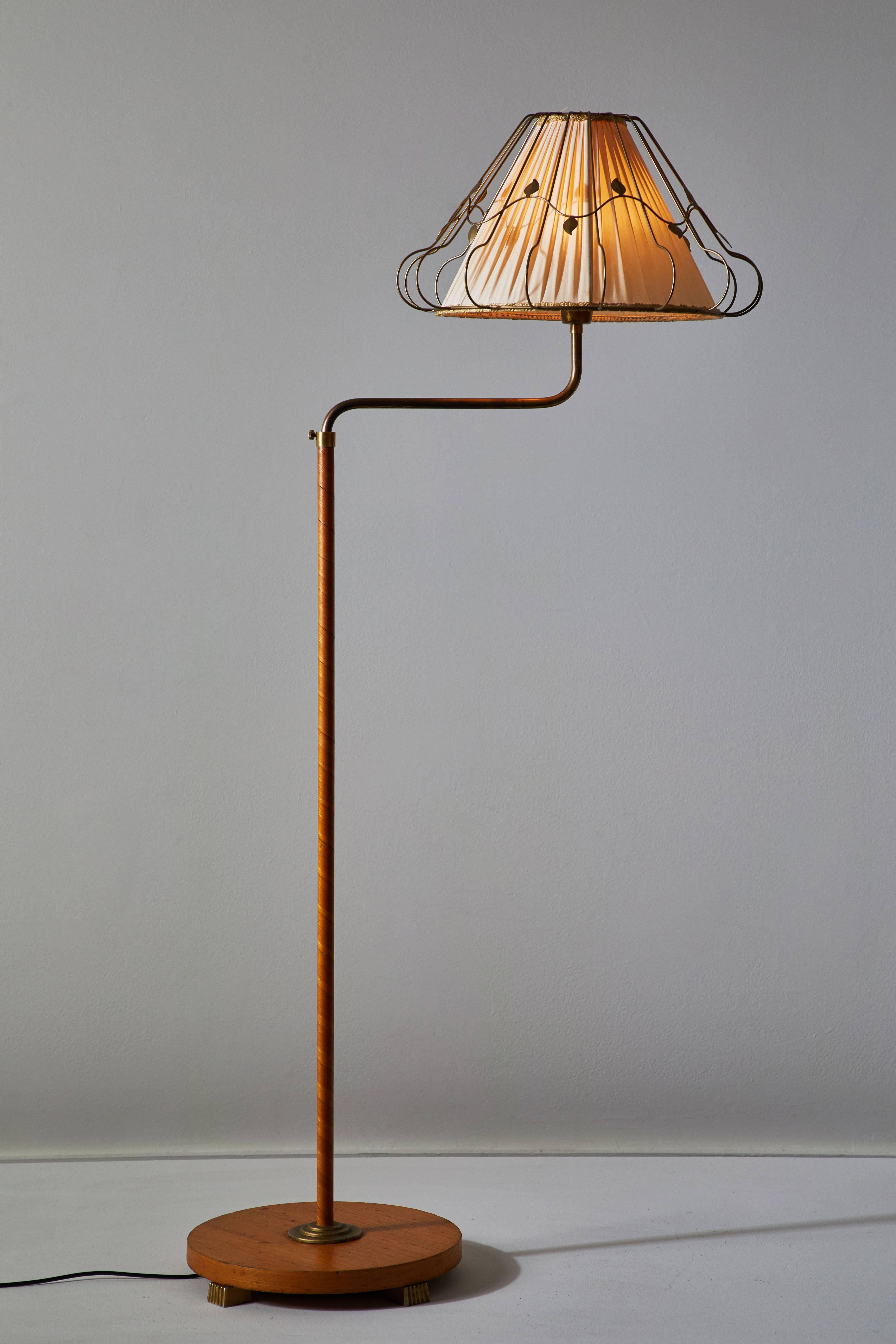 Rare Swedish floor lamp manufactured in Sweden, circa 1920s. Original cast iron legs on wooden base. Original silk shade with brass filigree. Original wood wrapped handle stem with brass handle that rotates left/right . Takes one E27 60w maximum