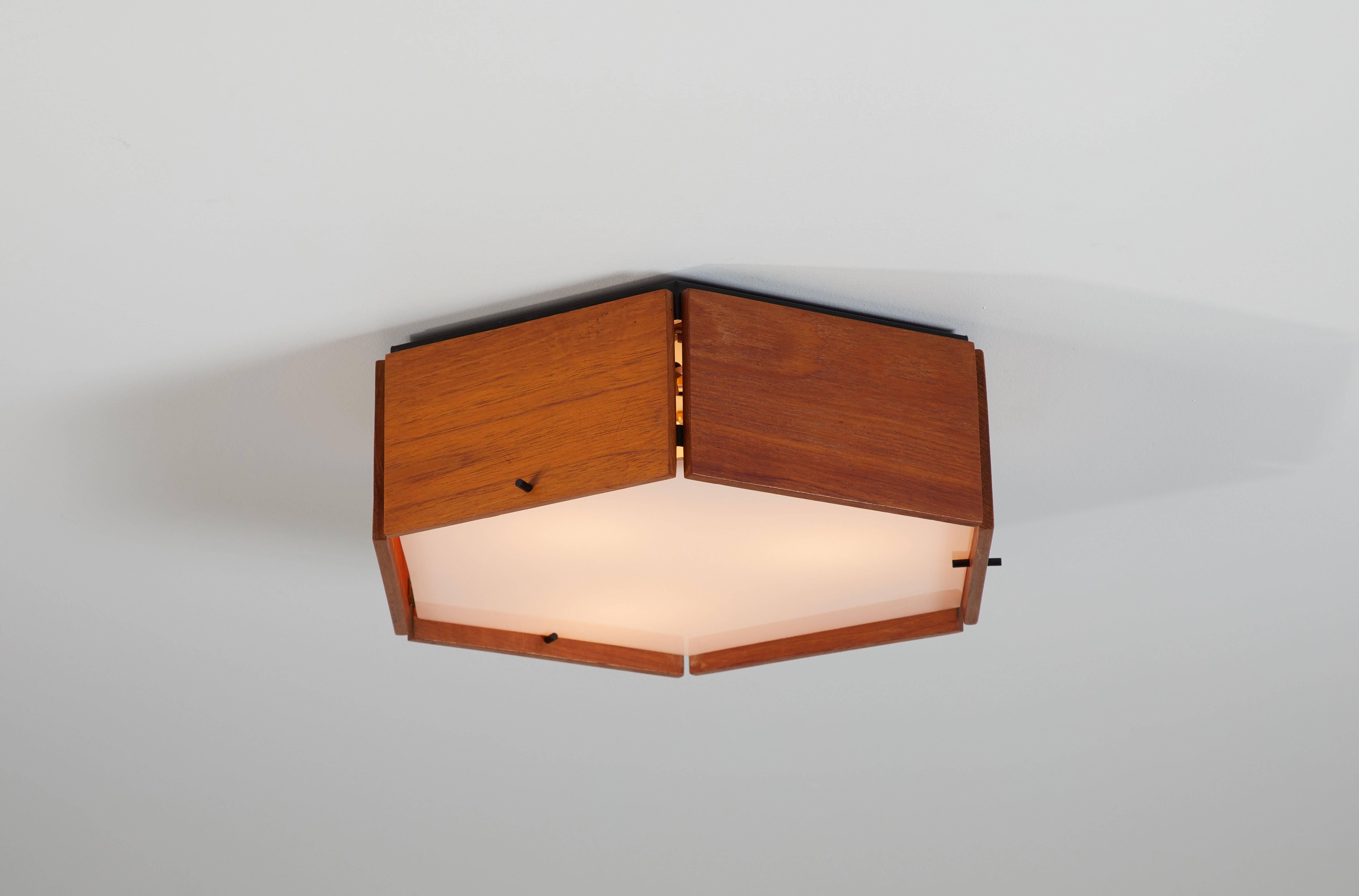Two teak and acrylic hexagonal flush mount ceiling lights by Reggiani designed in Italy, circa 1960s. Priced and sold individually. Wired for US junction boxes. Each sconce takes three E27 25w maximum bulbs.
