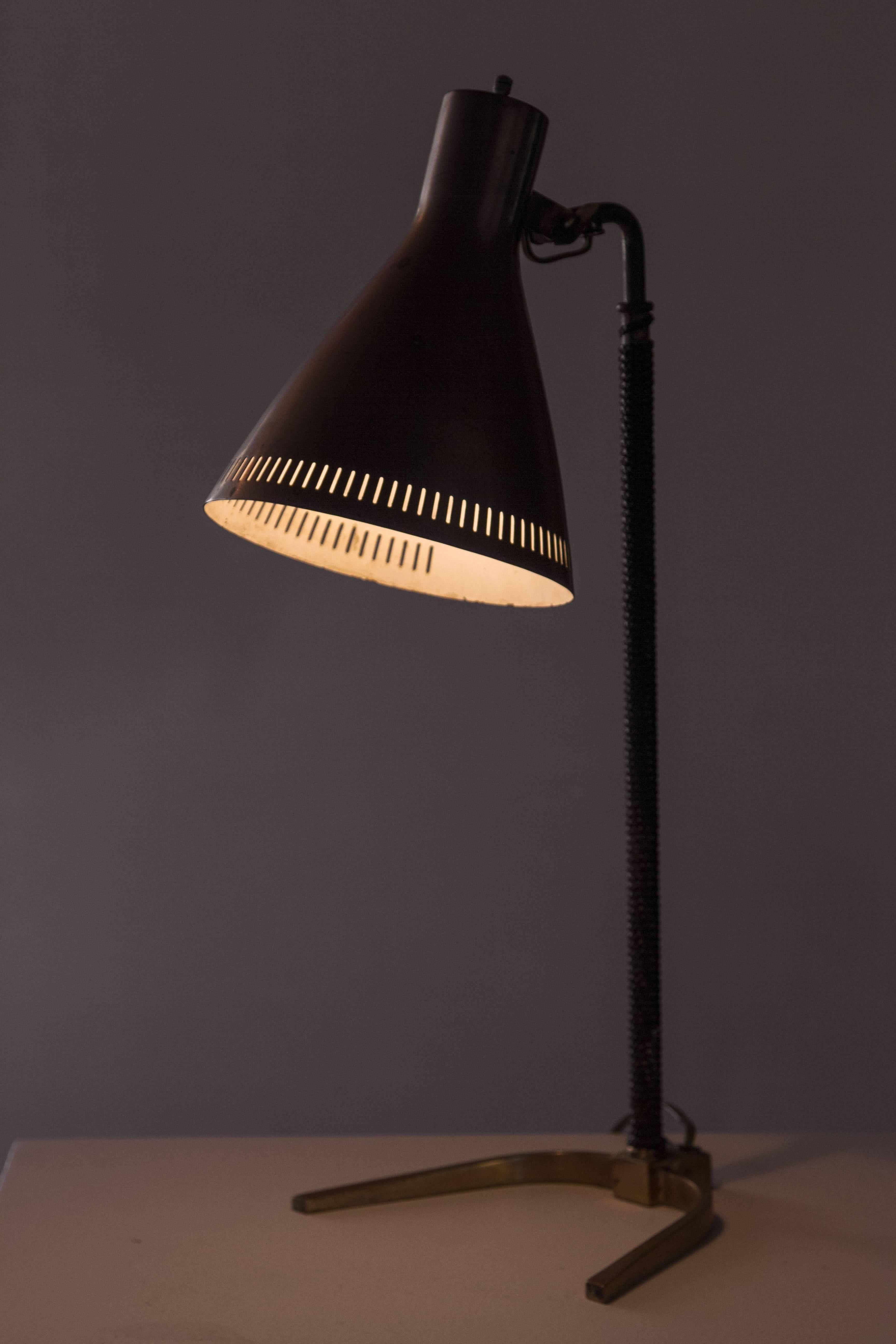 Brass table lamp with perforated, articulating shade. Original leather braiding on stem.
    