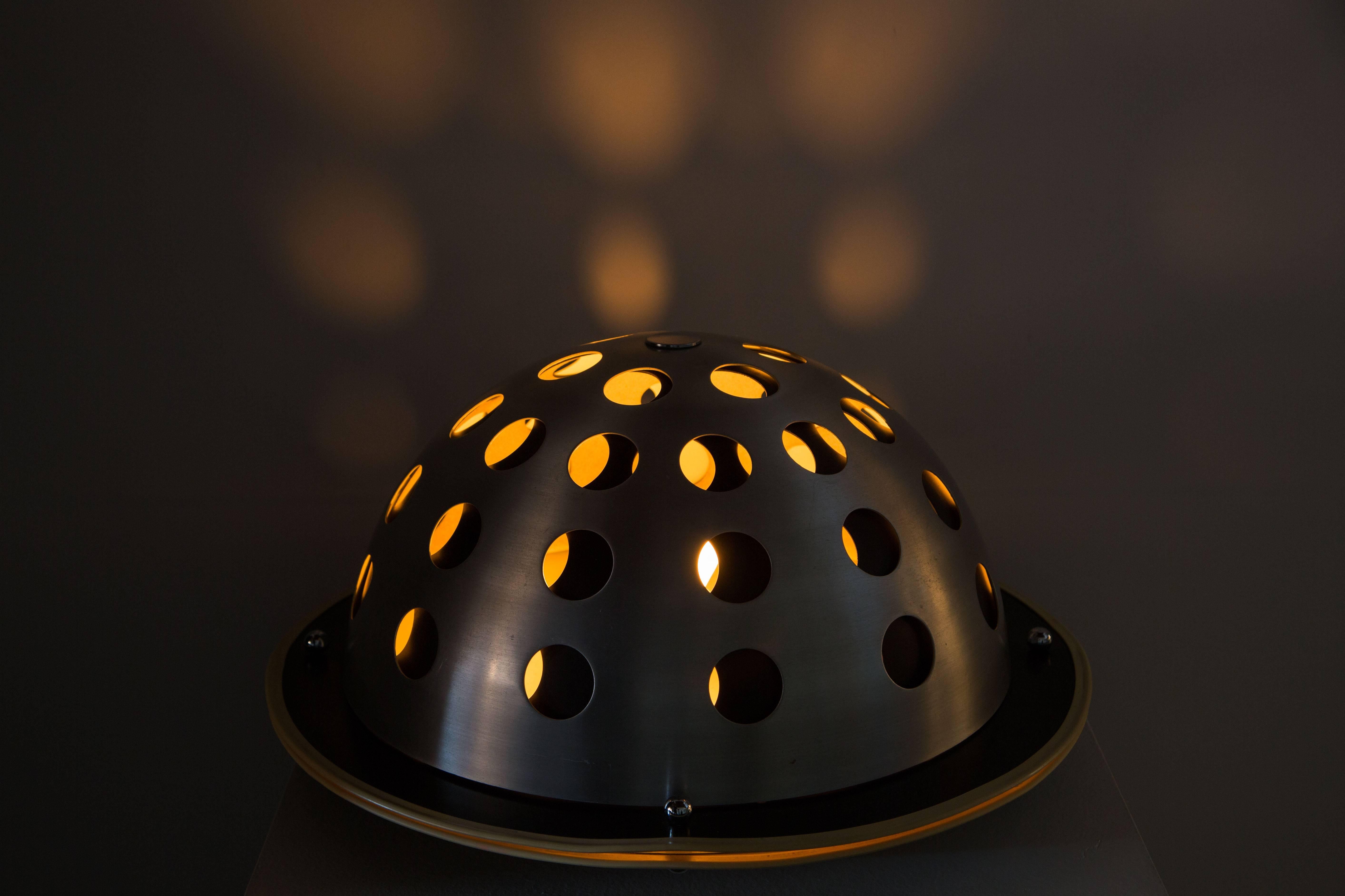 Lampe de table Elmo de Columbini & Guzzetti conçue et fabriquée en Italie, en 1973.  Acier brossé, avec de grandes perforations, métal laqué et plastique. Cordon d'origine. Accepte une ampoule E27 100w maximum. La deuxième quantité est disponible.
