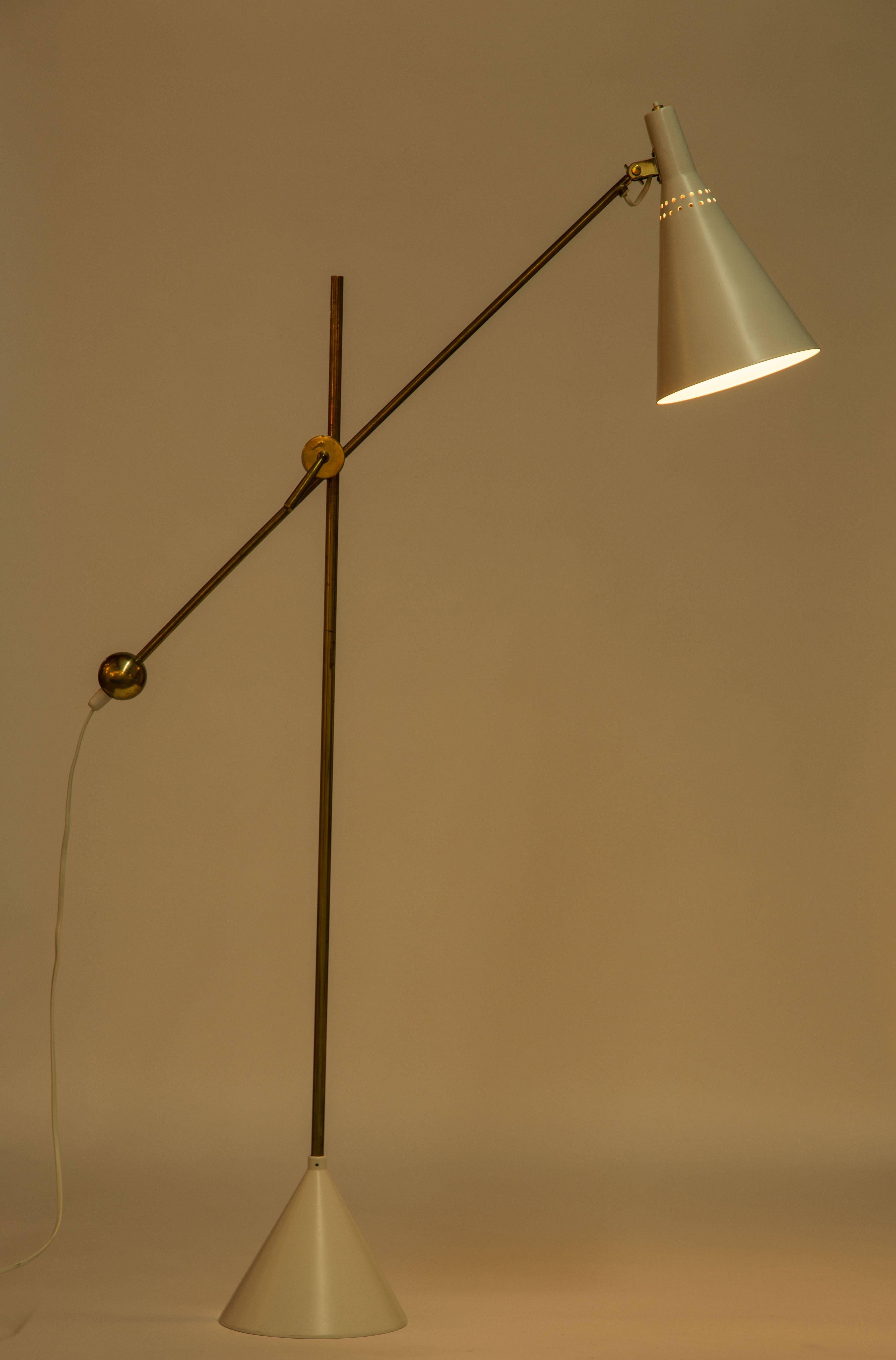 Brass and metal adjustable floor lamp with pivoting shade.