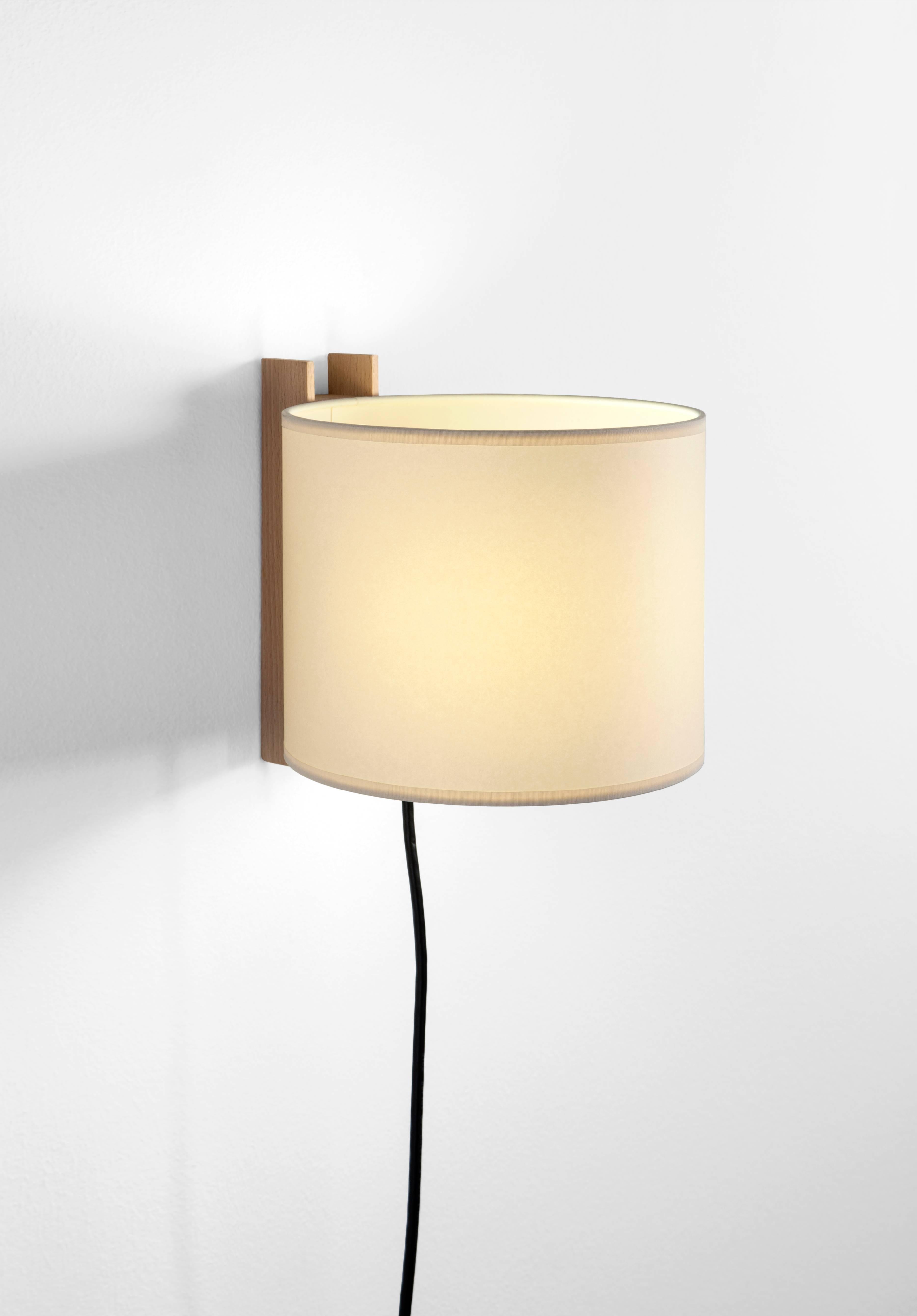 TMM Corto Wall Light by Miguel Mila for Santa & Cole. Originally designed in Spain in 1964. The TMM collection of short and long wall lamps comprises a simple beech channel into which the white or beige parchment shade is partially inserted. The