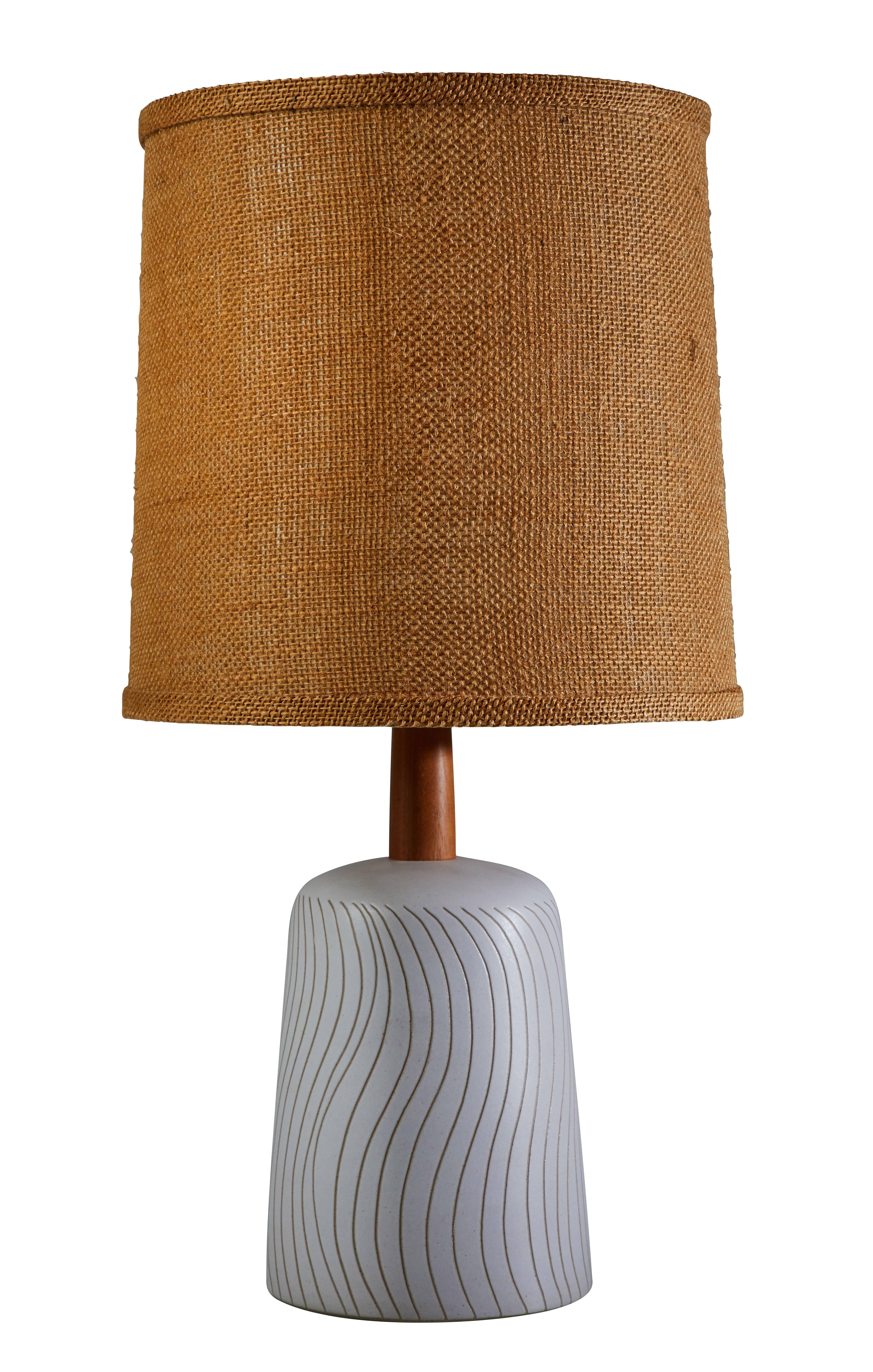 Ceramic studio table lamp by Gordon Martz designed and manufactured in the US.  Original burlap shade, wooden stem and finial. Sgraffito lines to base. Original cords. Retains original signature. Takes one E26 75w maximum bulb