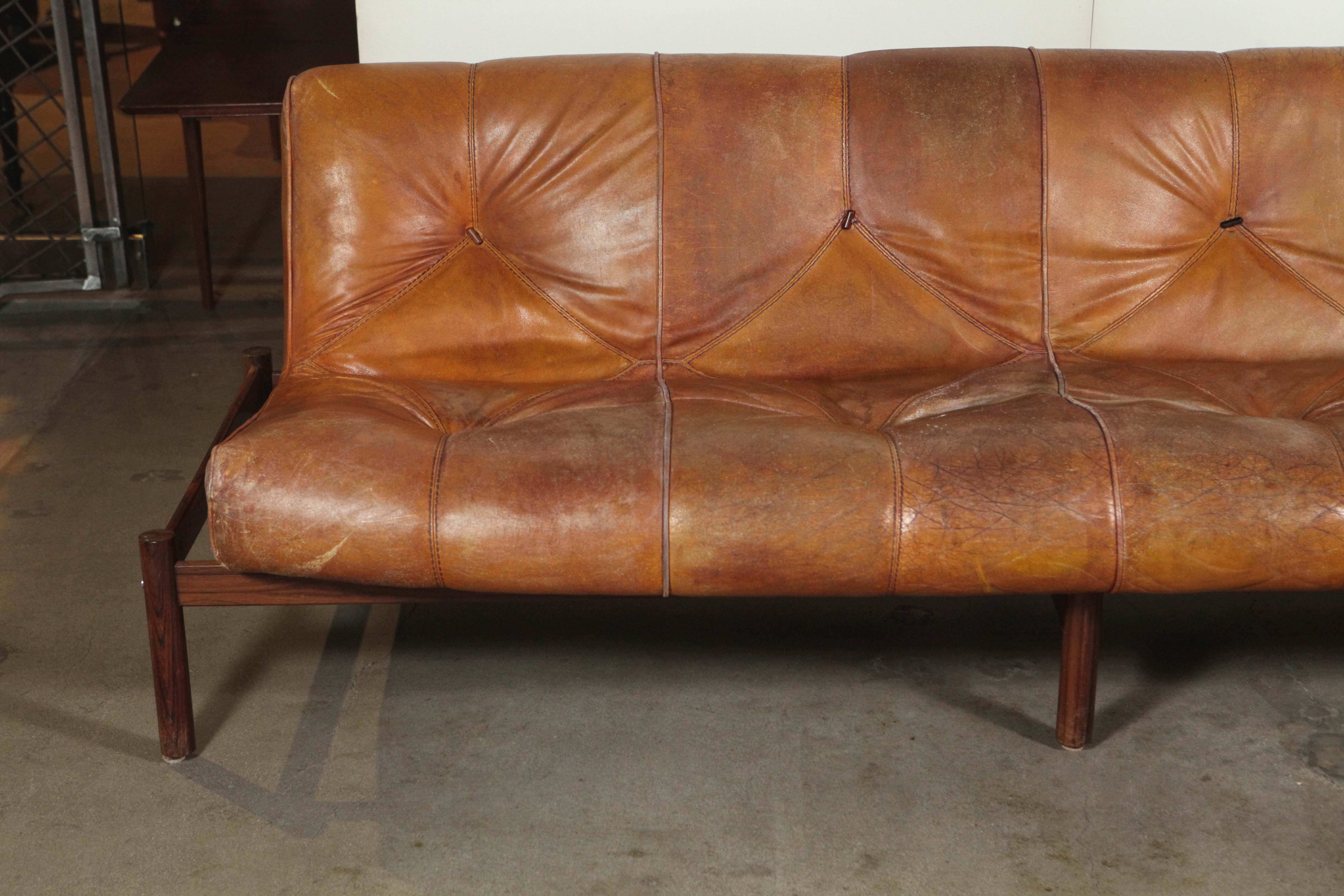 Brown leather single tufted Danish sofa on wood base.