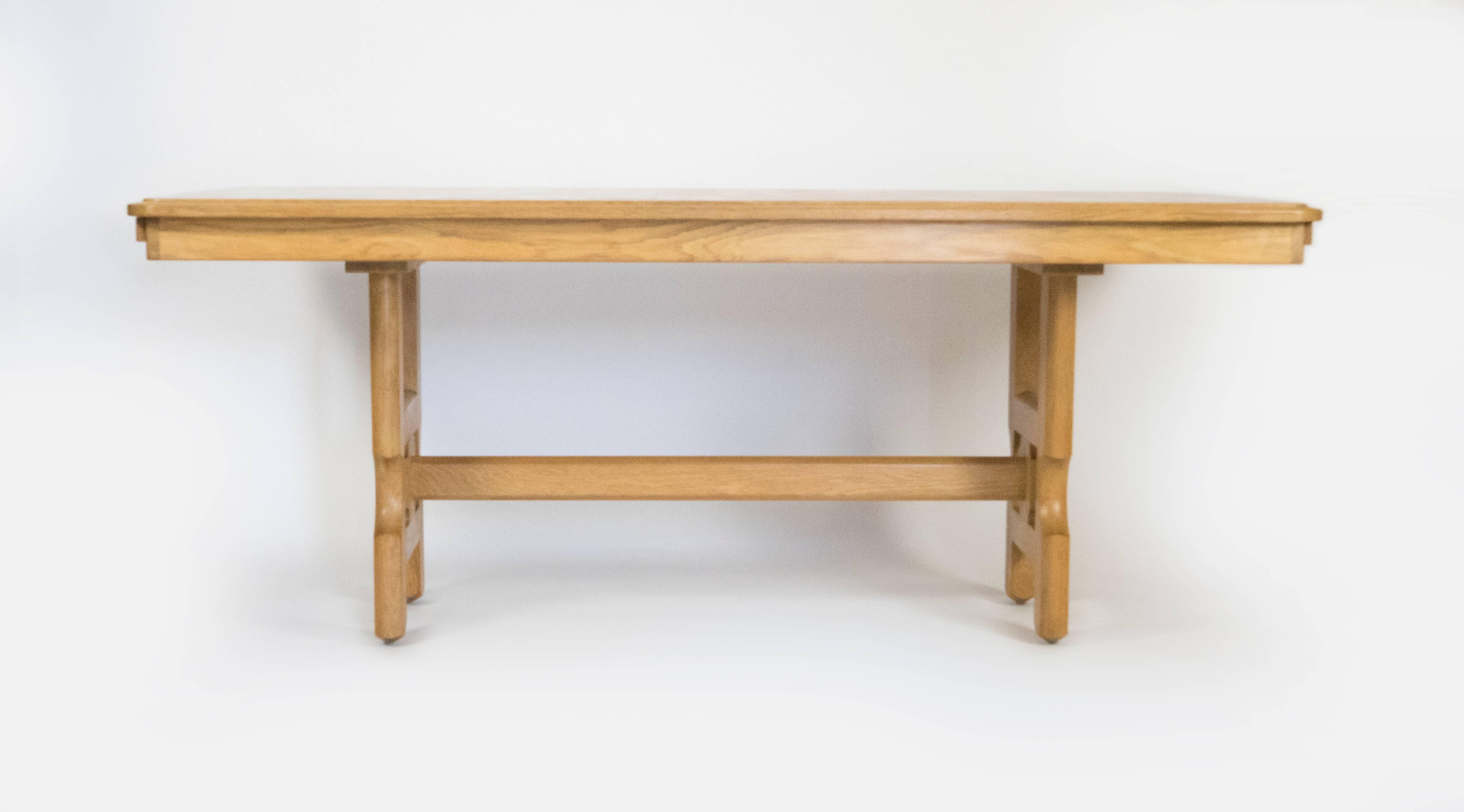 This beautiful table designed by Guillerme et Chambon for Votre Maison is in great condition. Crafted from solid oak, the carved legs encase a carved medallion. The table has two finished leaves with the same design as the top which adds an