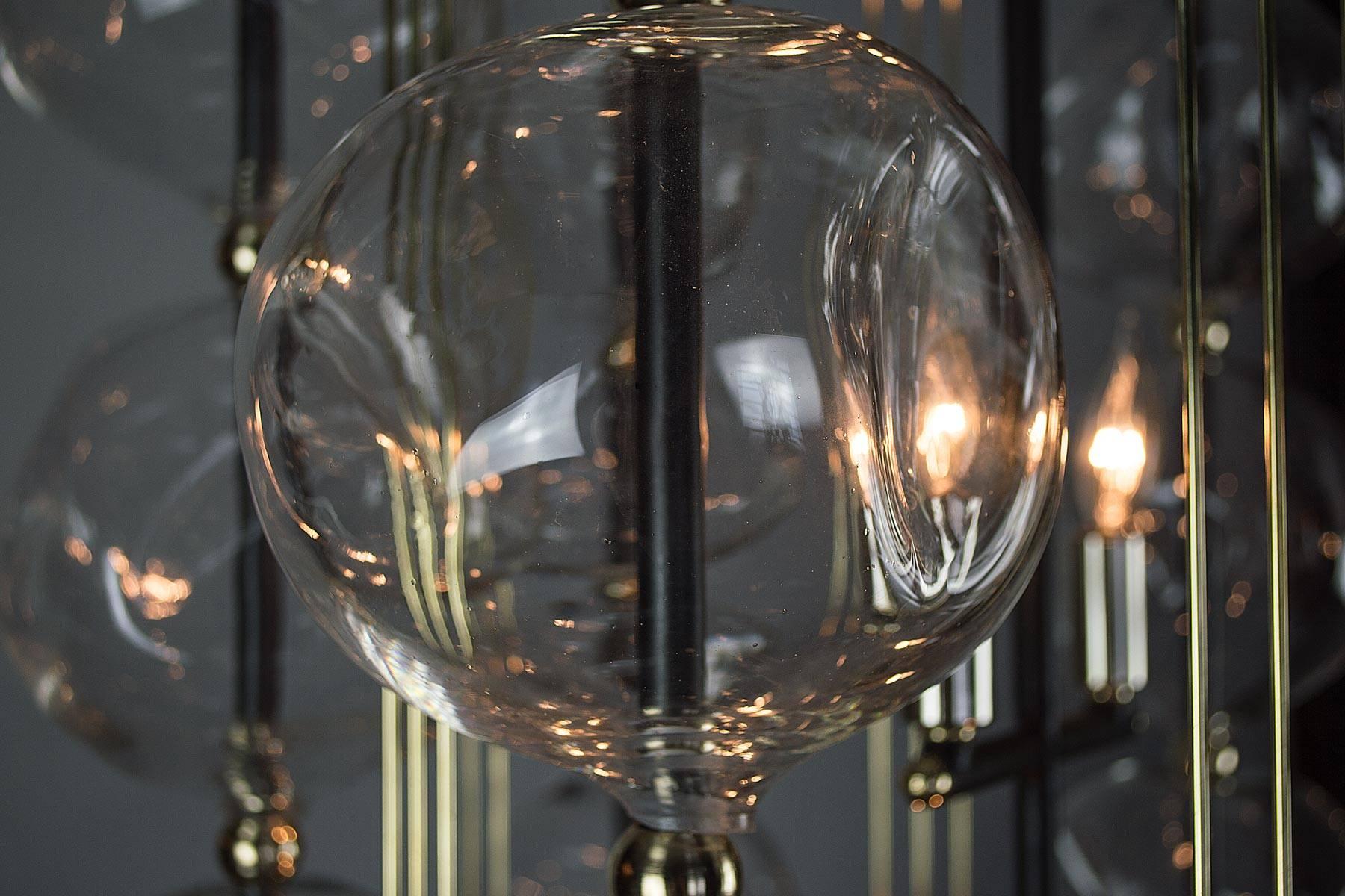 A fresh expression of the Classic lantern created to accentuate the shimmering light which reflects in the many contours of the glass. The handblown glass orbs with their asymmetrical shapes are assembled on a hexagonal gunmetal steel frame. The