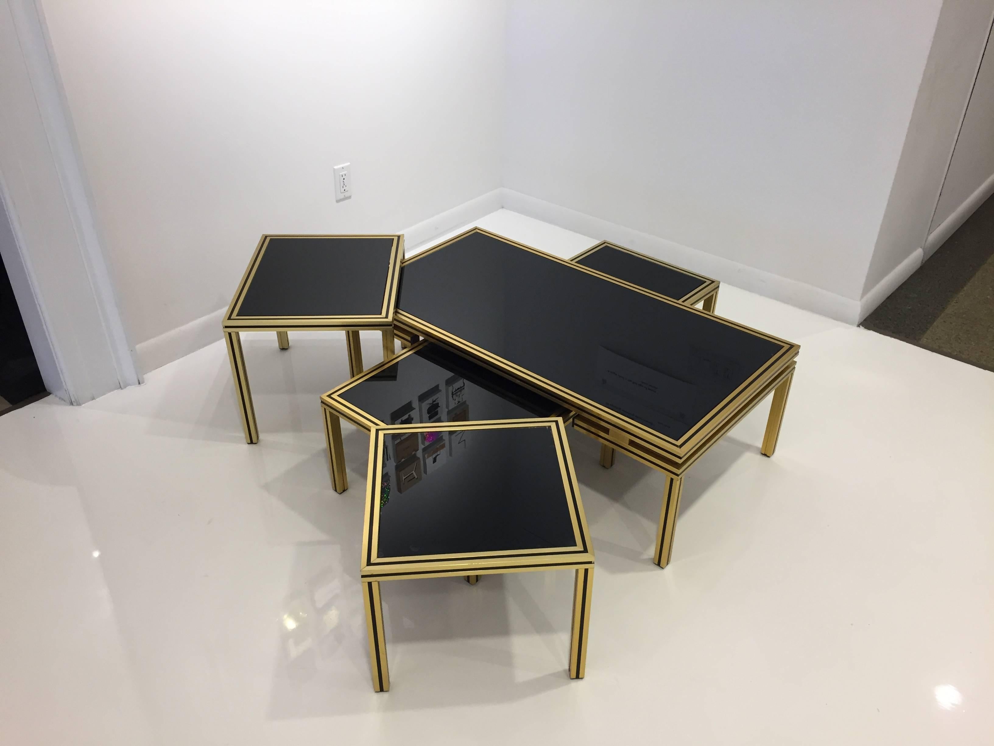 Five tables of the same design which are perfect as one large multi-layered coffee table or as one coffee table with a separate set of three nesting side tables. Brass coated aluminum frames with black insets, painted glass tops.
Measure: Table