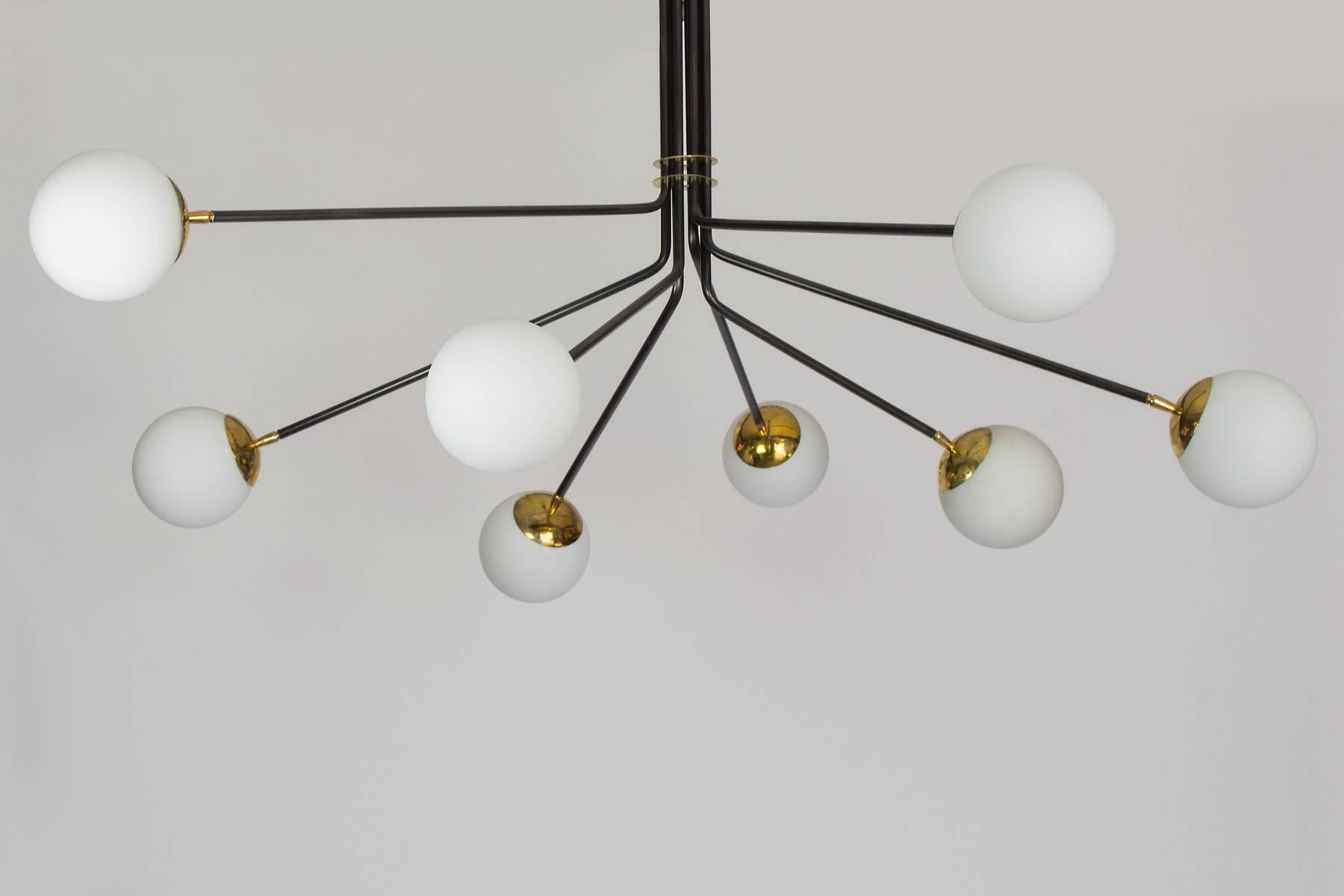 This chandelier combines brass, opaline glass and black enamel to create a wonderful Mid-Century inspired chandelier. The eight lights provide a lot of light, it is a large-scale chandelier which will work nicely in an entry or a dining room. The