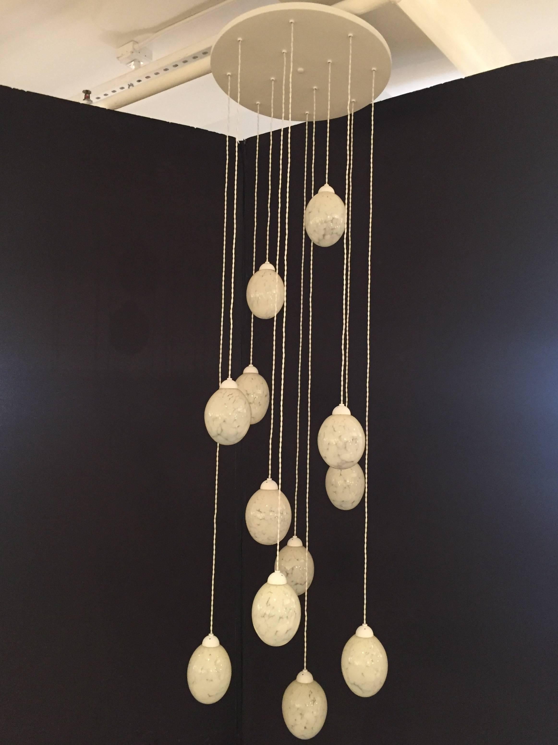 12 handblown globes suspended from a circular canopy. White enamel finish with white silk twisted wire. Wires can be shortened on site. Each glass diffuser hold one candelabra based bulb 40 watt max. 