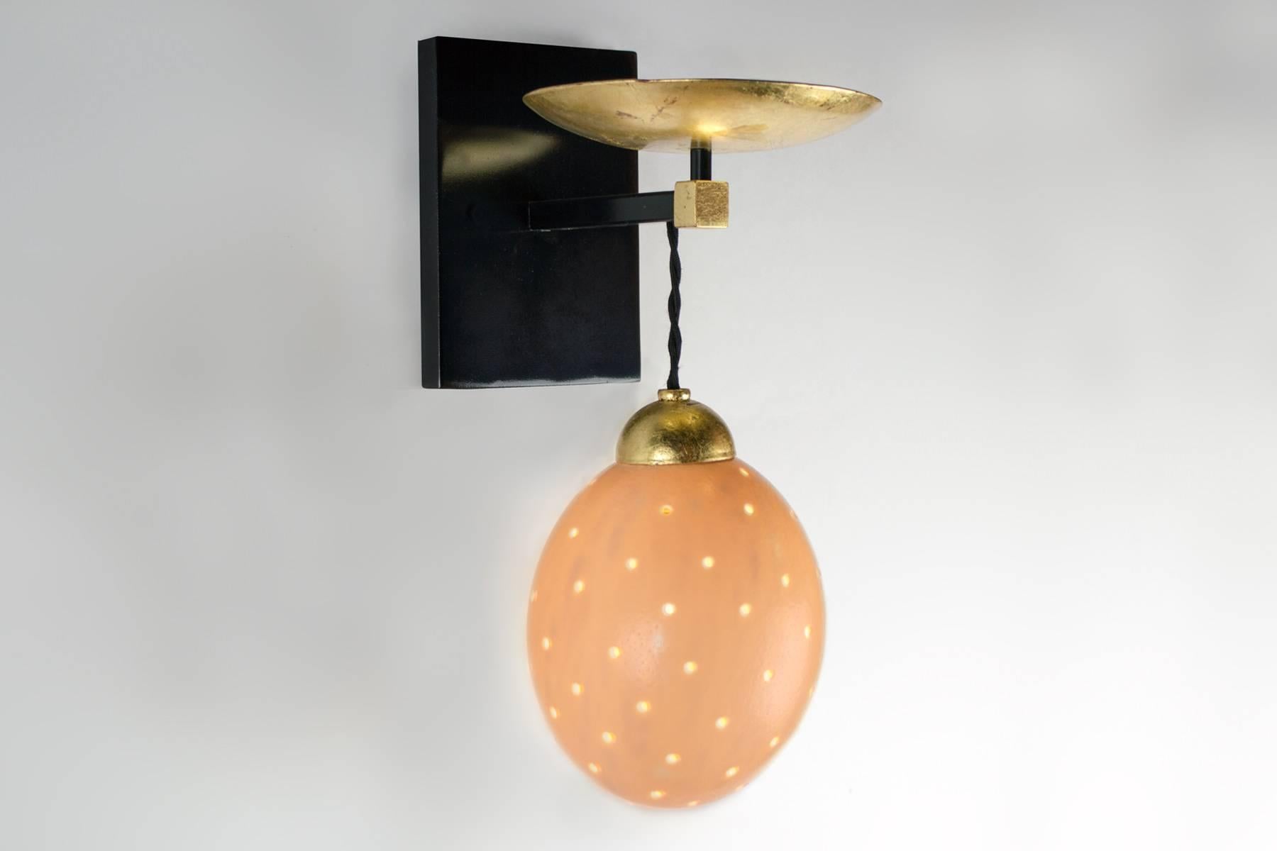 These unique lights, with a black enamel frame and gold leaf accents, have a real ostrich egg diffuser. The braided silk cord can be adjusted. Fixture uses one candelabra based socket, (25 watt max egg diffuser).