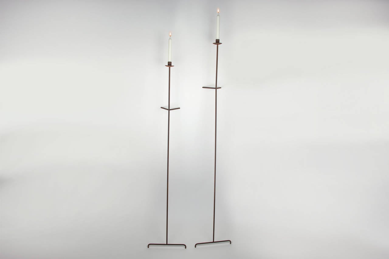 Two versatile candle holders. They lean against the wall and can be place almost everywhere to provide lighting. These candle holders are steel with a gun metal patina. They each use one taper candle each.