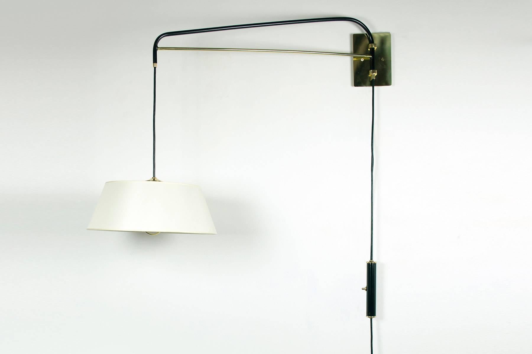 These graceful wall sconces are handcrafted by Bourgeois Boheme Atelier. They are made with a black enamel finish and polished brass. An elegant linen shade diffuses a soft light. These fixture are adjustable, the switched counter weight system