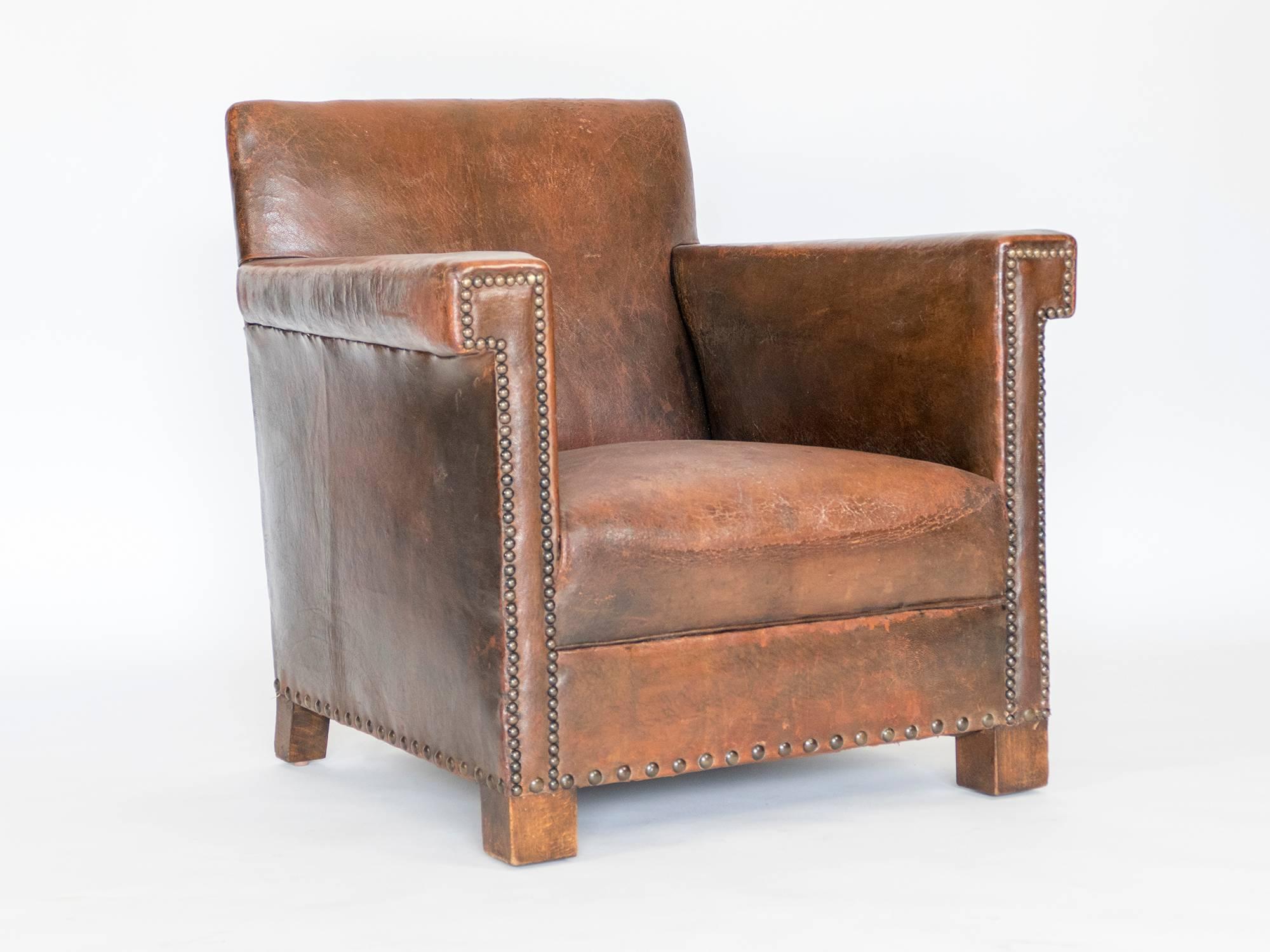 Two leather arm chairs with original leather.  Smaller is scale and very comfortable.  We have restore the chairs, so they are very solid.  Great nail head details on the arms, front and back.  Springs have been tightened and leather is in good