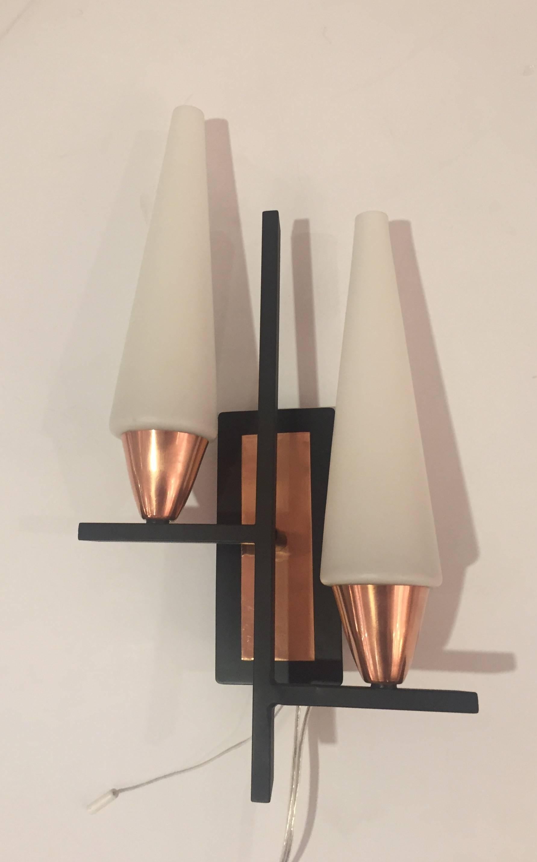 Two geometrically inspired wall sconces with copper accents and opaline glass diffusers. Each light has two European based sockets (adapters to American bulbs are provided). They also have a switch wire on each wall support. The back plates have
