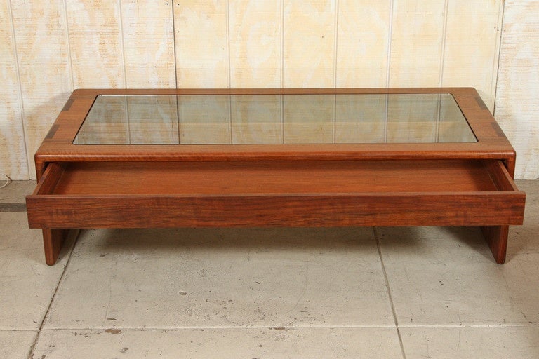 Shedua coffee table with clear glass top and drawer with exposed contents, by Gerald McCabe for Orange Crate Modern.
