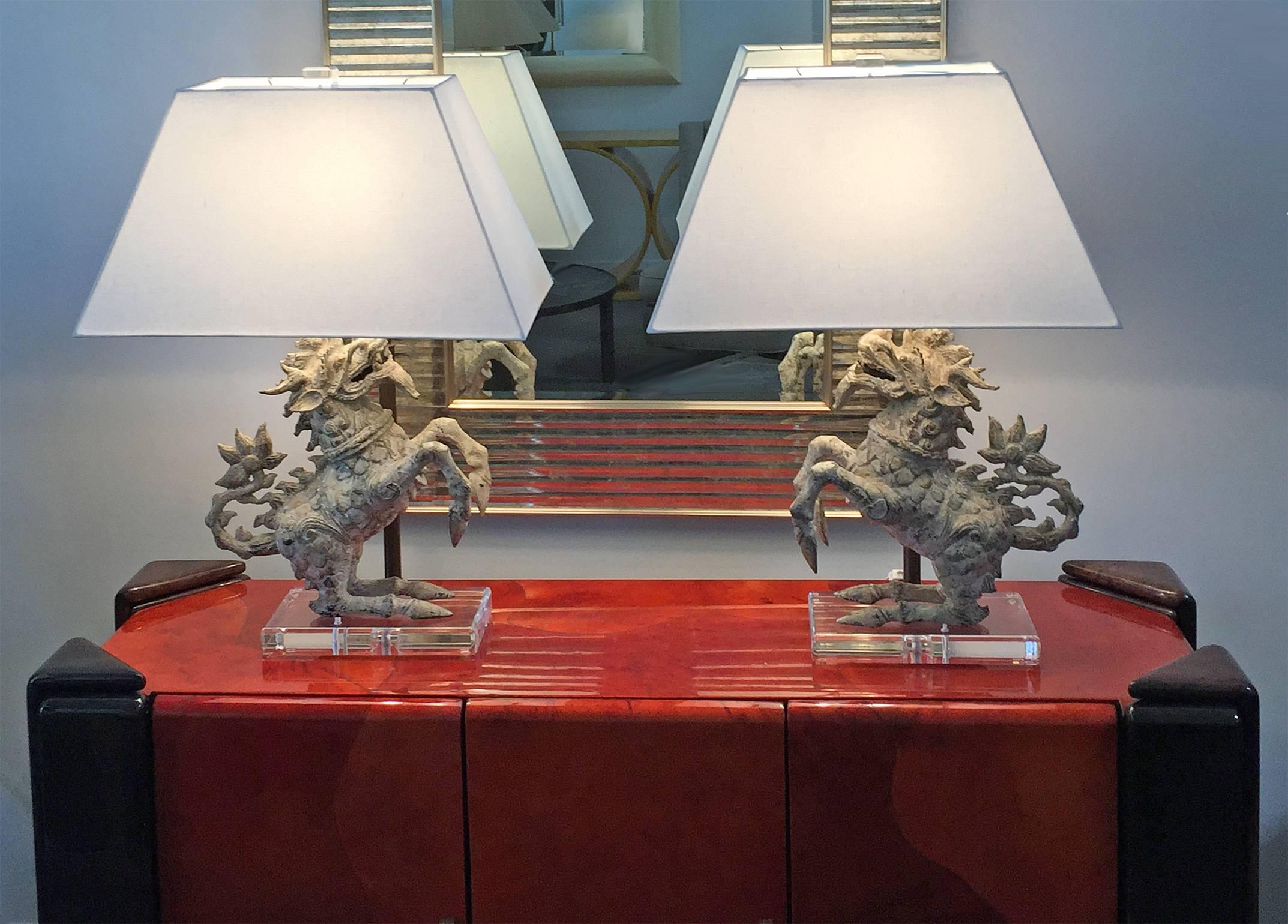 Pair of table lamps featuring patinated metal Foo dogs mounted on heavy Lucite bases. New custom silk shades. Top quality materials and craftsmanship. Price is for the pair. Shade measures: 23