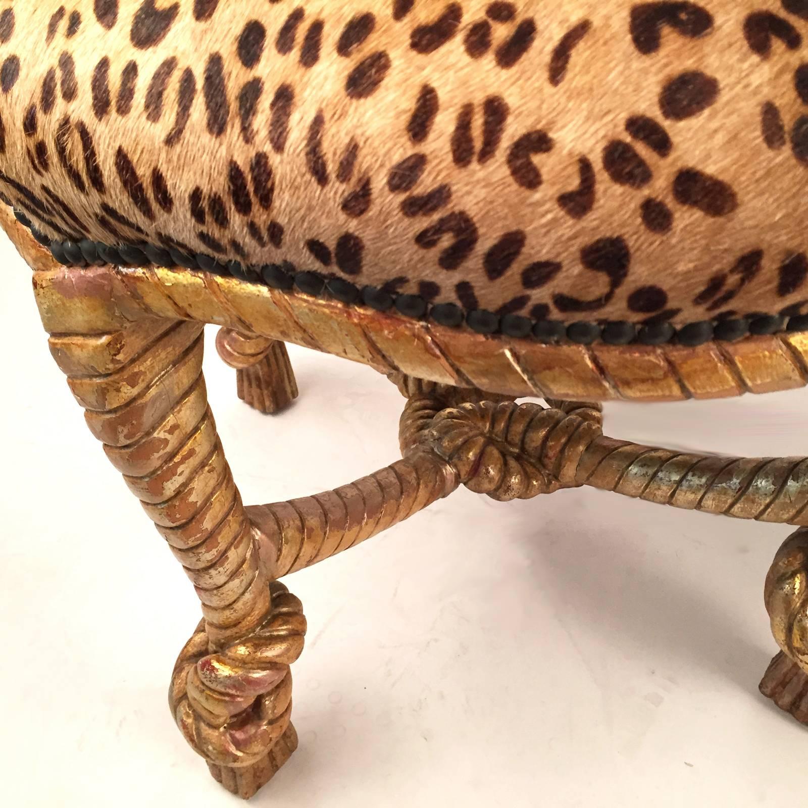 1970s glamorous pair of matching stools. Covered in leopard printed cowhide. The bases are carved wood with an antiqued gilt finish. Price is for the pair.