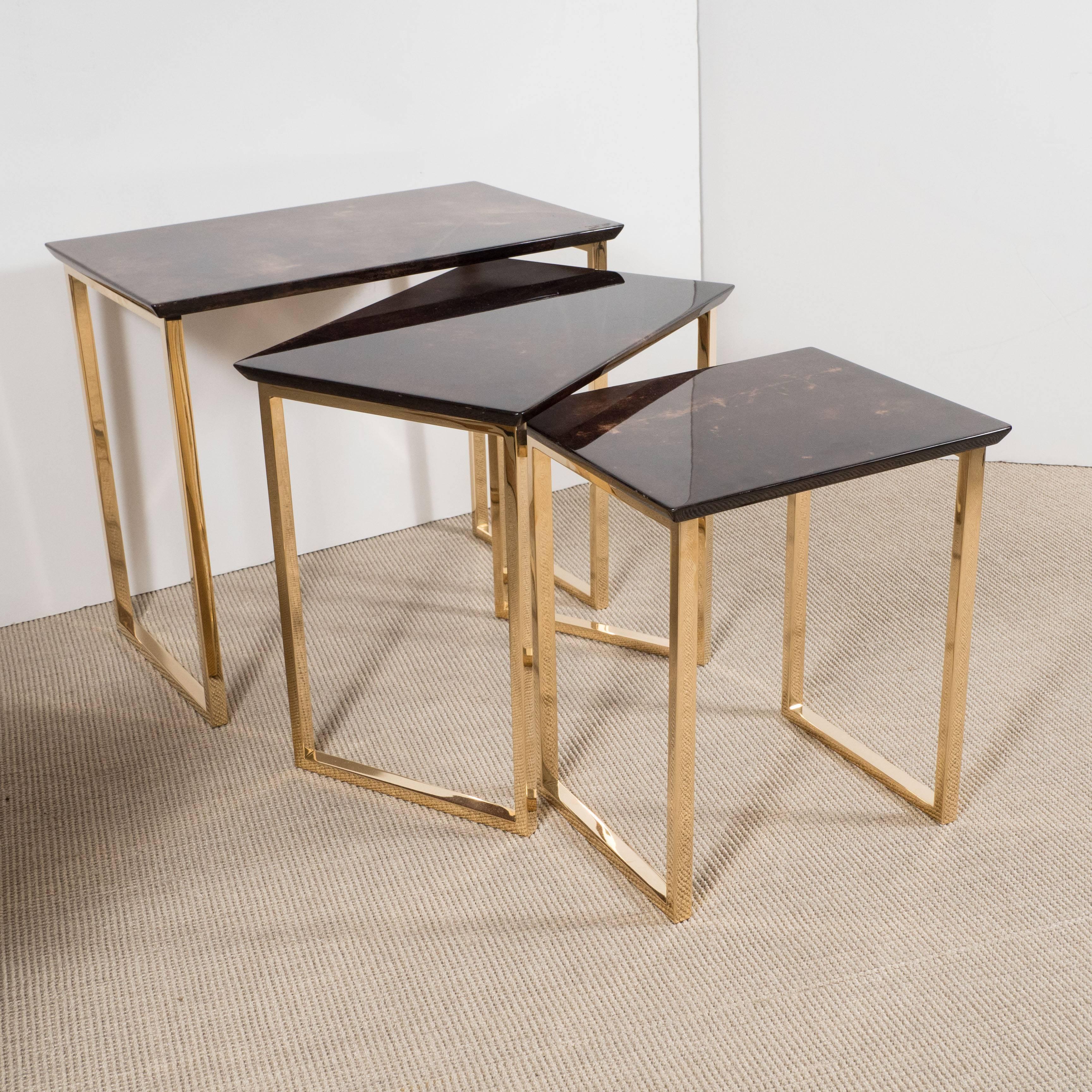 Set of three aldo tura parchment rectangular nesting tables with polished bronze. Largest: H: 10 to 17 10 to 0 by 12 in. 

Lacquered parchment and solid mirrored bronze.