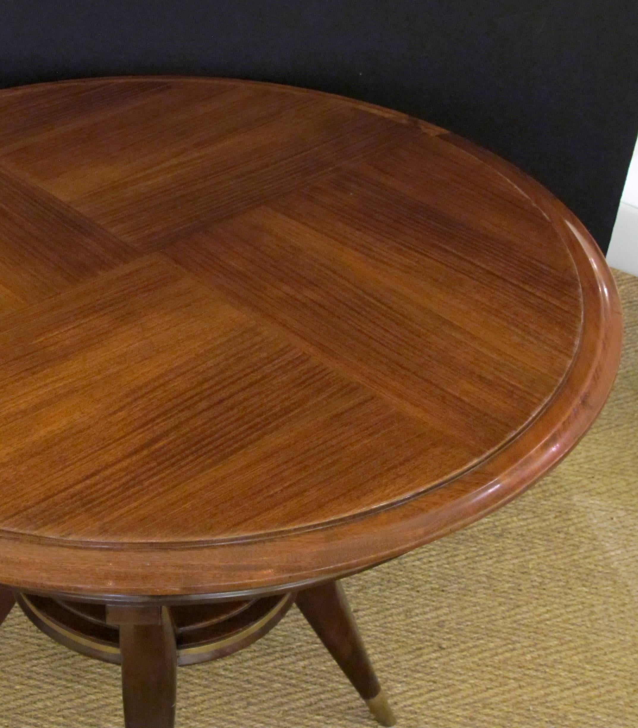 A stylish Italian 1950s circular game table with reversible top; the well-figured mahogany top flipping to reveal a parchment surface; raised on graceful splayed supports with ring stretcher.