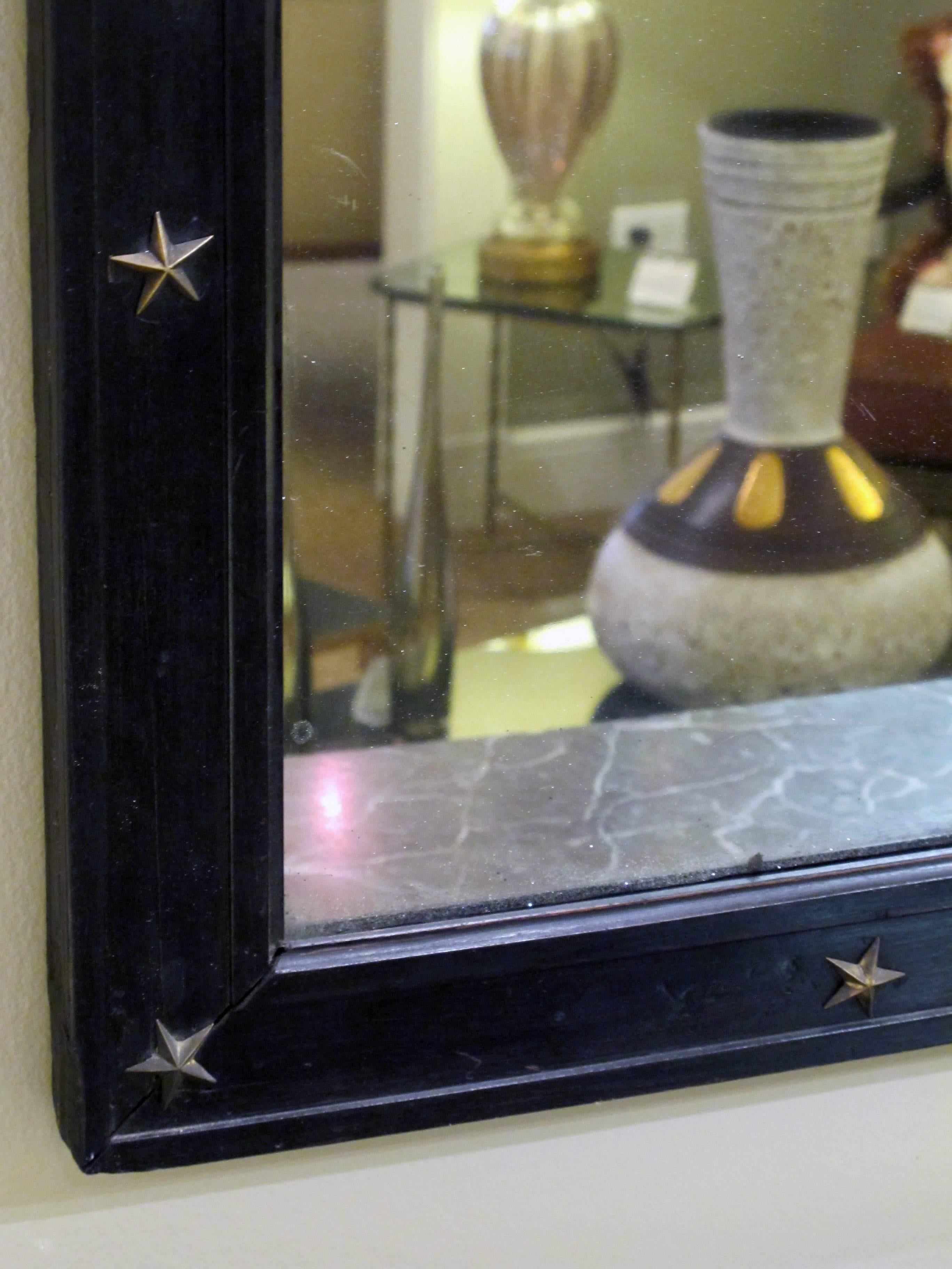 A large French Louis Philippe rectangular ebonized mirror with applied bronze stars; the original split mirror plate within an ebonized wooden frame adorned with bronze stars