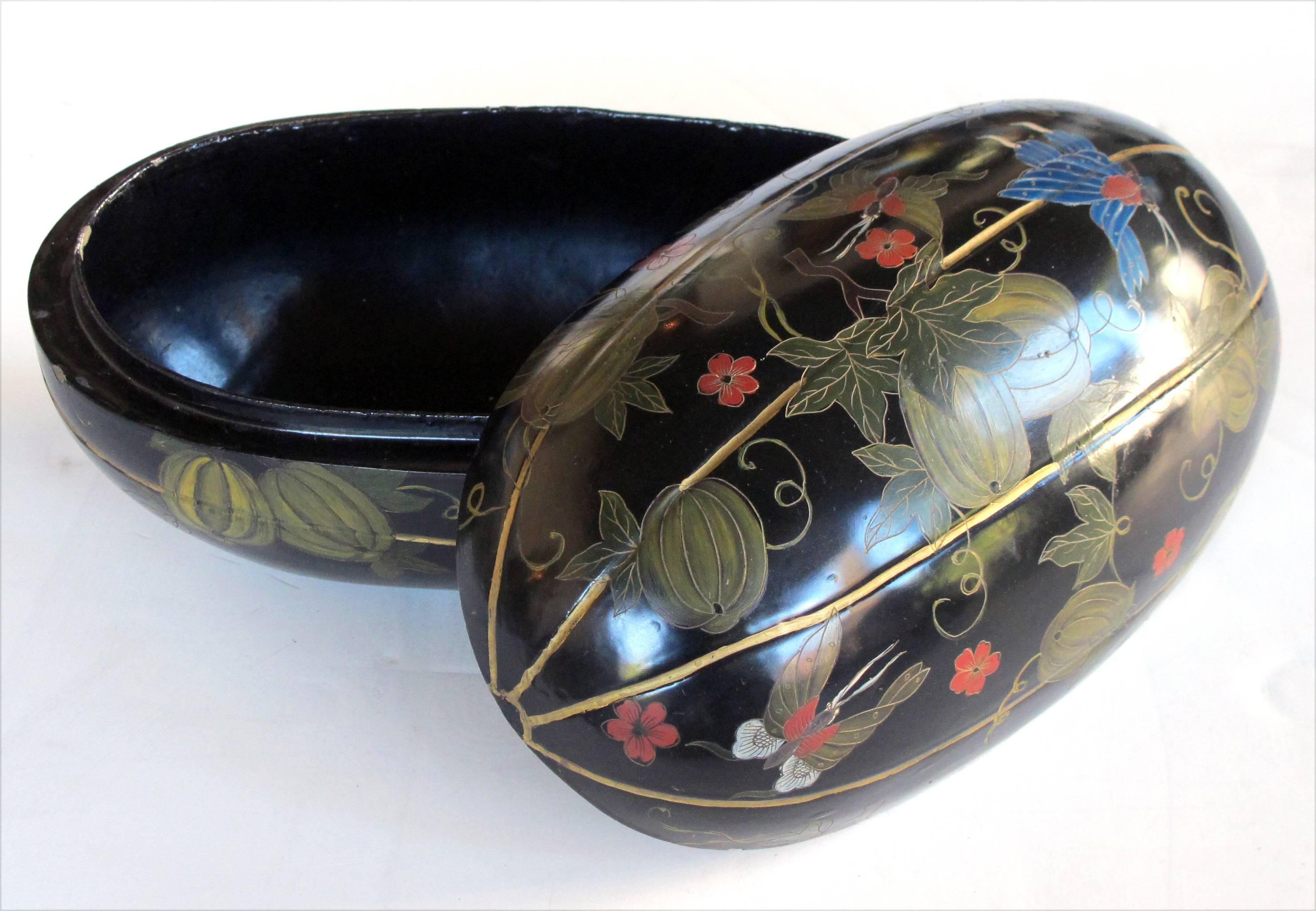 A delightful Japanese black lacquered hand-painted gourd-form box; the oblong lidded box adorned overall with delicate butterflies amid a meandering floral vine laden with plump gourds.
