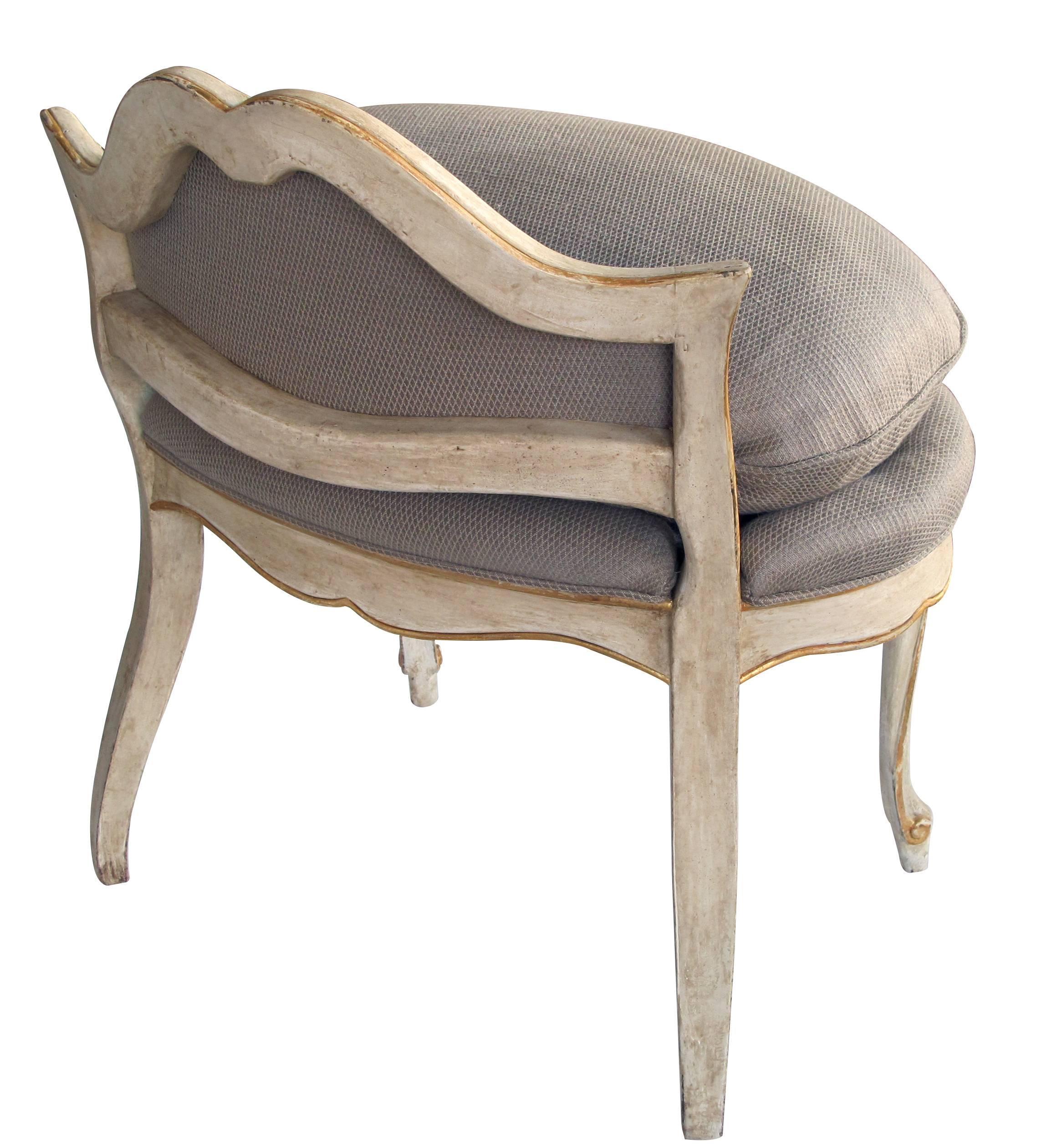 An elegant French Louis XV style ivory painted and parcel-gilt low back stool perfect for dressing room or end of a bed; with low shaped back above an oval padded seat raised on graceful cabriole supports.
