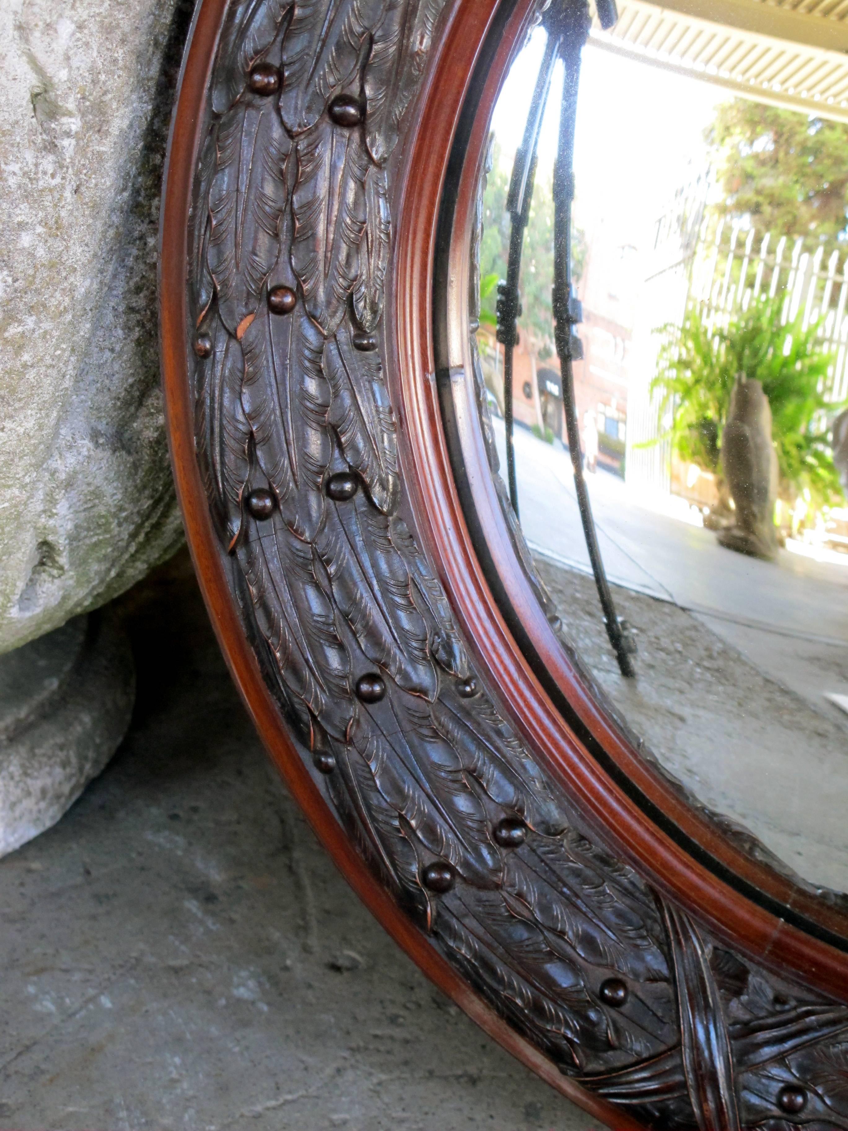 A well-carved English Victorian convex mirror with laurel leaf frame; the circular convex mirror within a thick well-carved walnut frame.