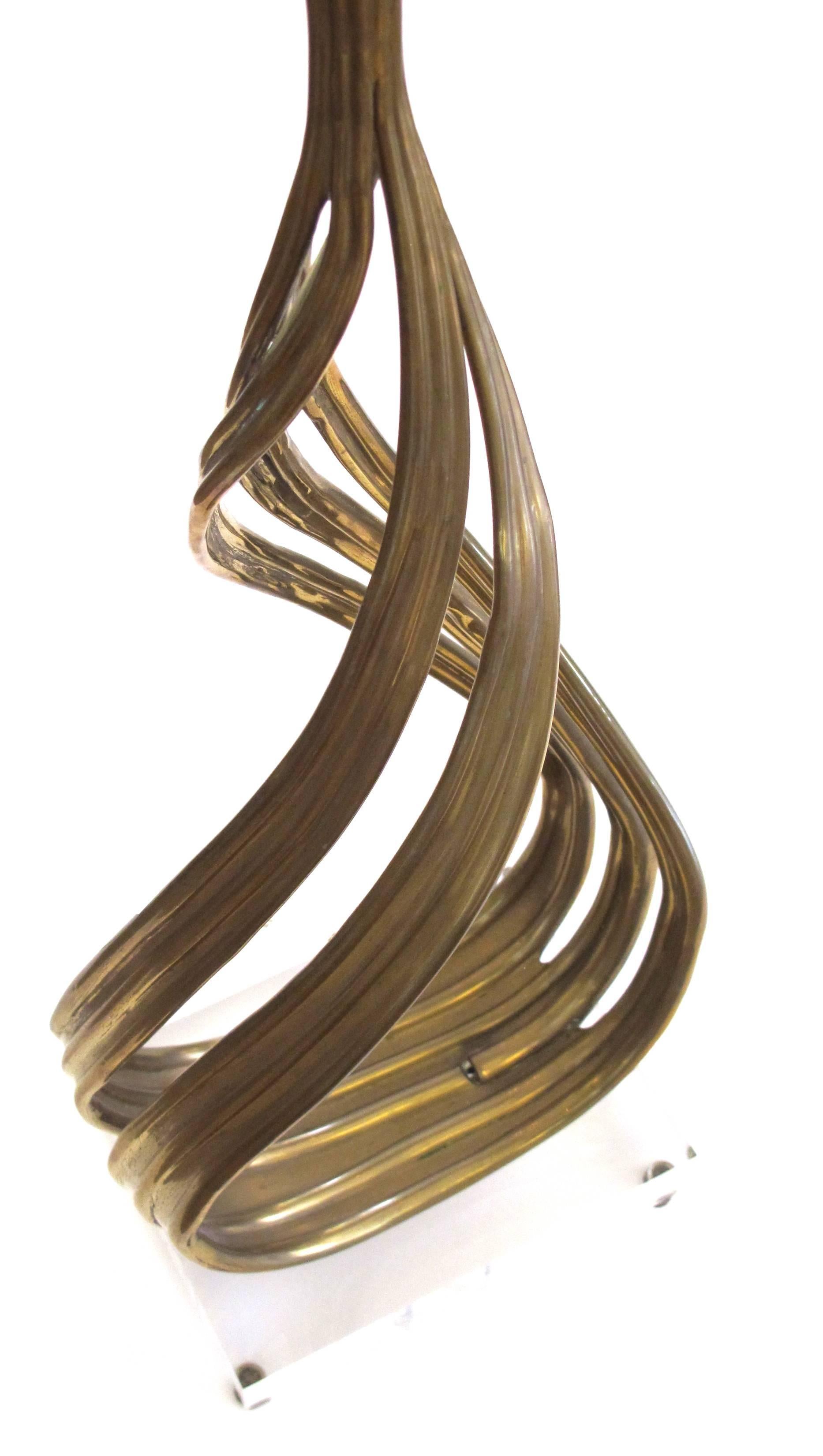 The teardrop shape consisting of brass tubing; resting on a Lucite base