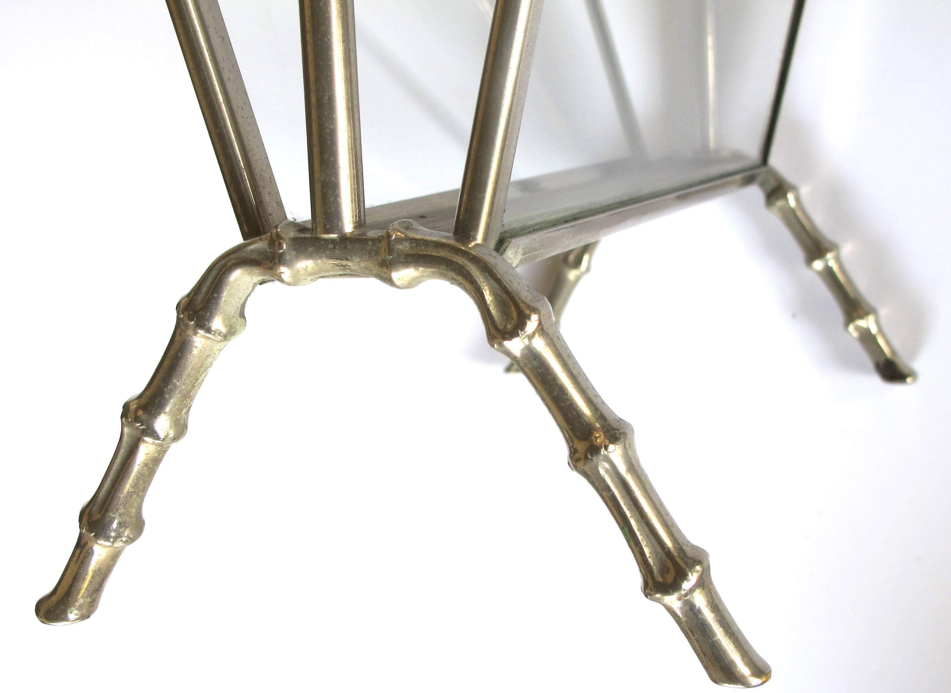 A chic and stylish French Masion Bagues 1940's chrome and glass faux bamboo magazine rack; with arching faux bamboo handle joining a glass framed receptacle over faux bamboo legs