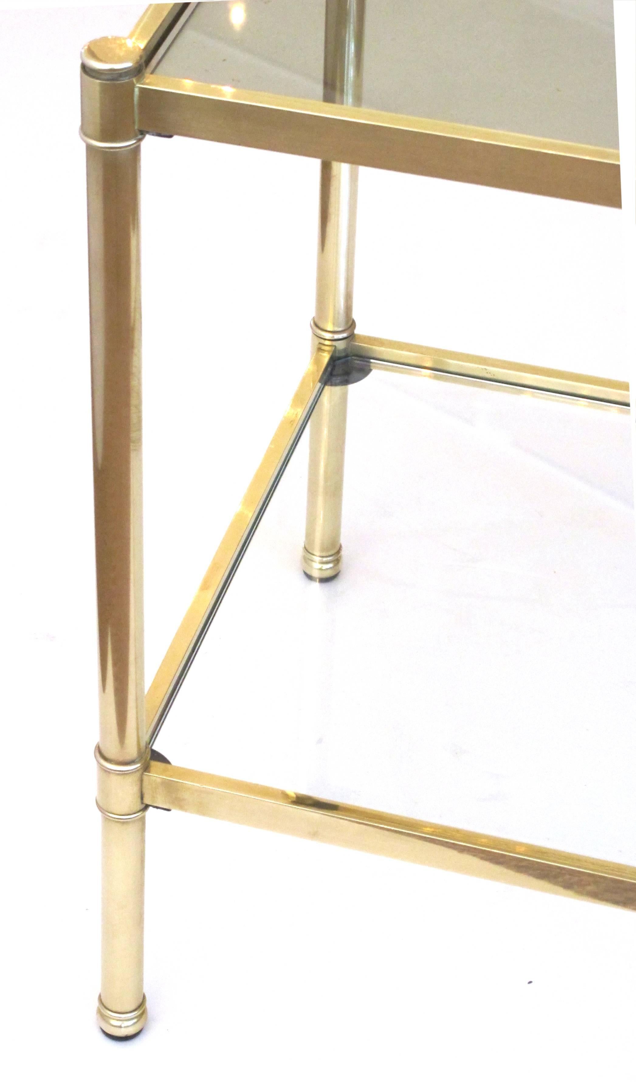 A good quality pair of French Roche Bobois 1980s solid brass square side tables with glass tops; each with glass inset top all within a brass frame raised on cylindrical supports joined by a lower glass shelf.