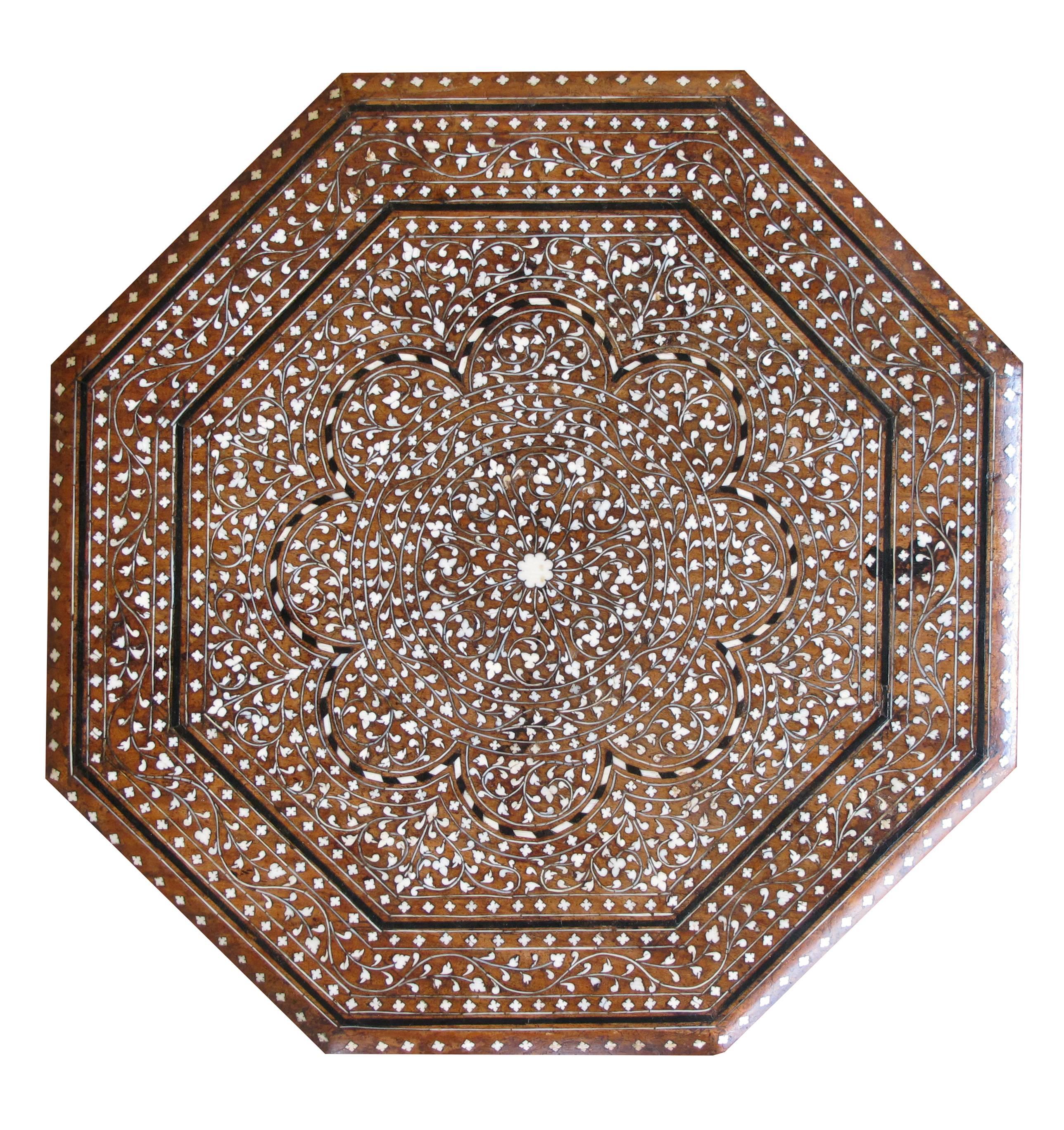 A finely inlaid Anglo-Indian octagonal traveling table; the octagonal top centering an inlaid stylized floral medallion within a foliate band; raised on arabesque supports.