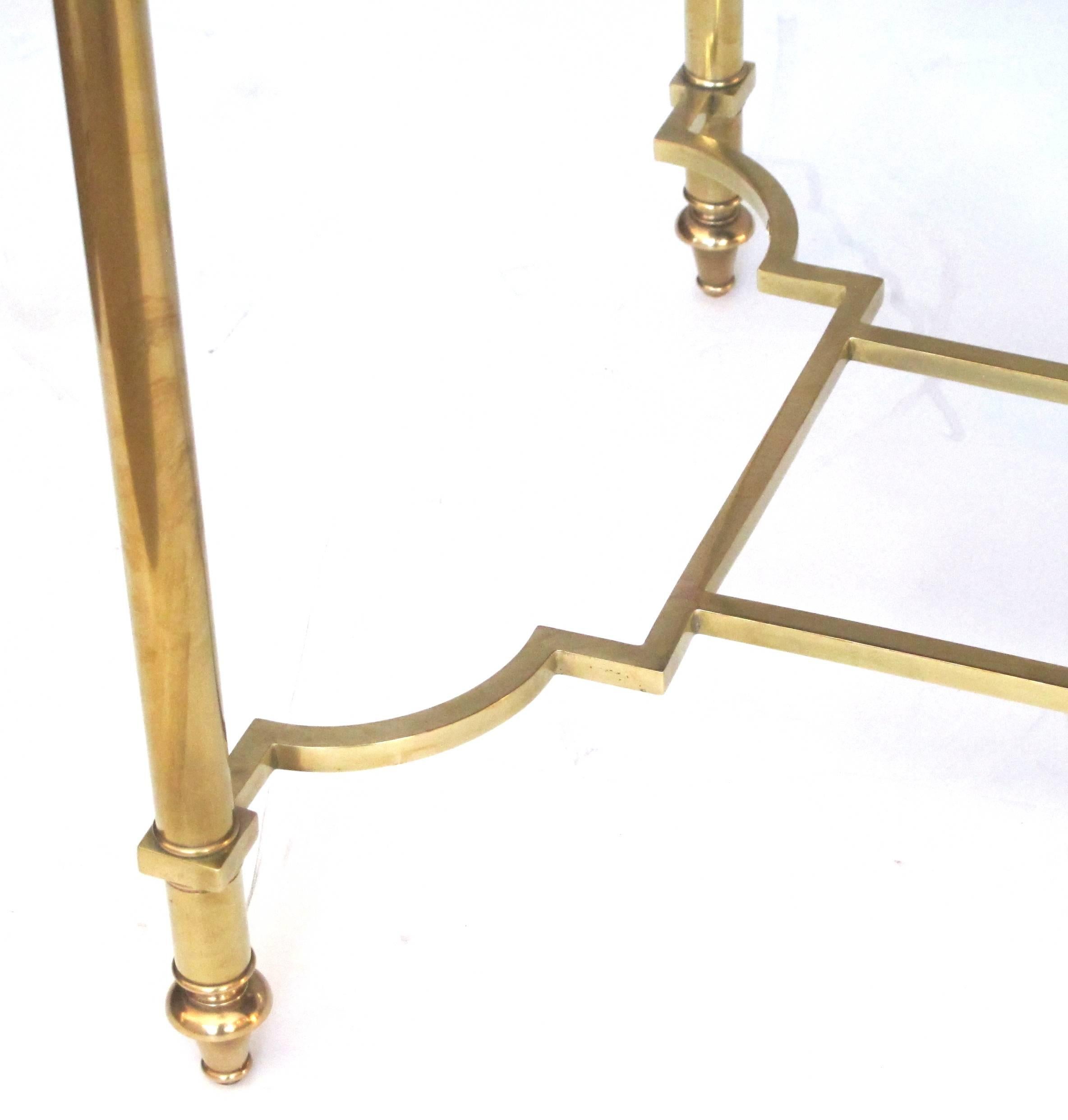 A stylish French Mid-Century neoclassical style rectangular brass coffee or cocktail table with mirrored top; the mottled mirrored top within a brass frame raised on columnar supports all joined by a shaped stretcher.