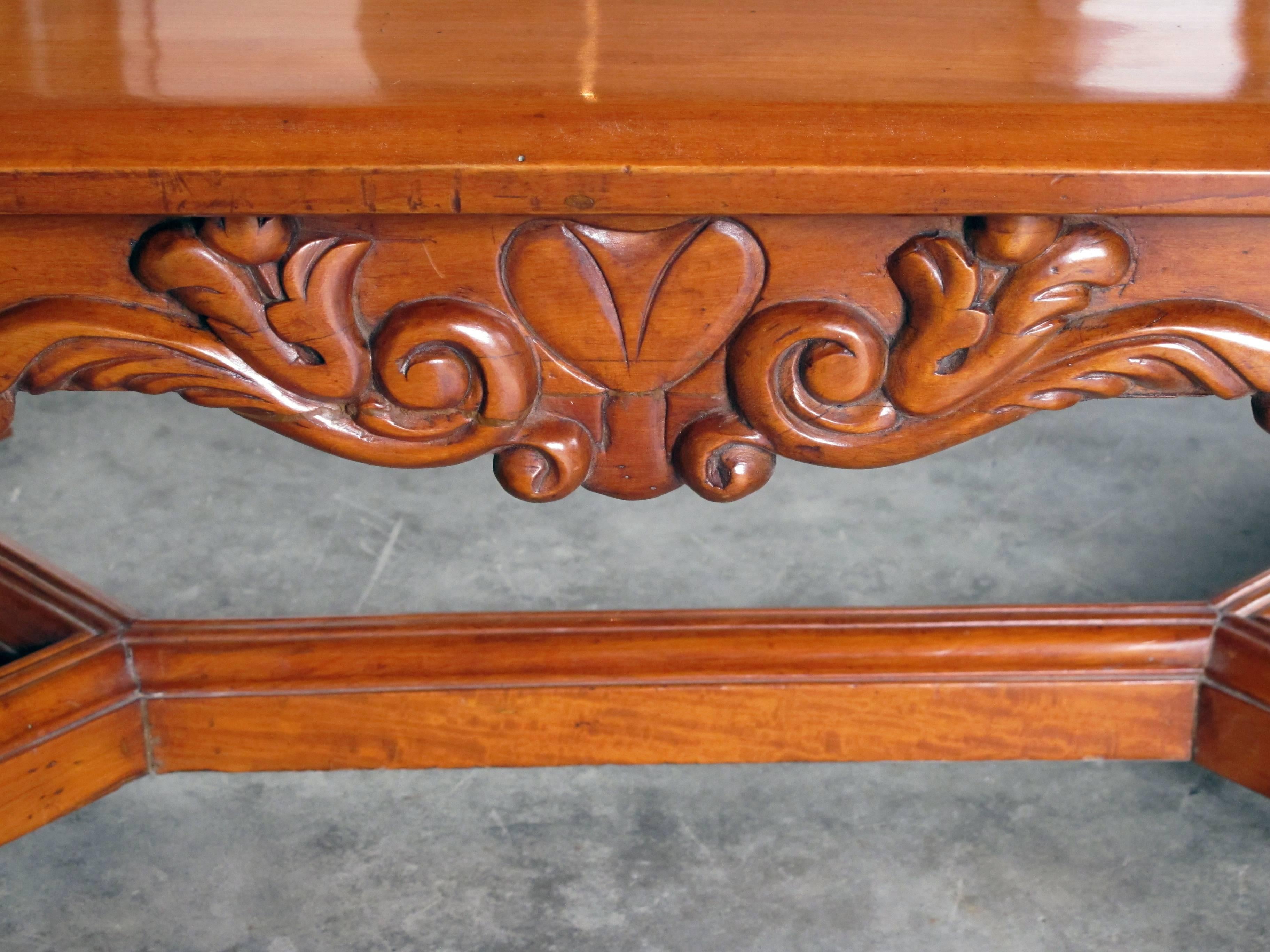 A handsome and boldly-carved French Baroque style cherrywood coffee or cocktail table with canted corners; the richly patinated solid cherrywood rectangular top with canted corners above a conforming base raised on four boldly scrolled open-work