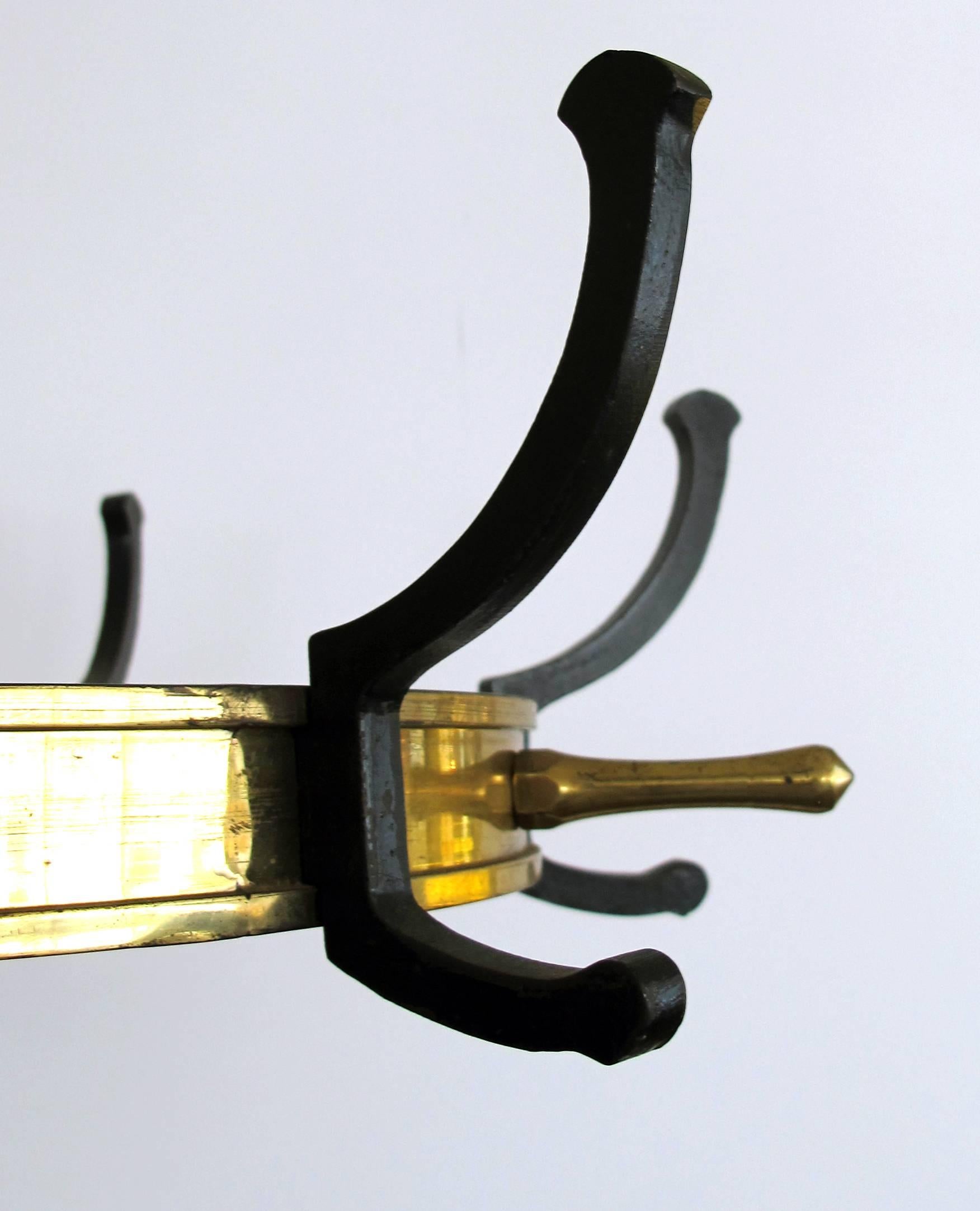 A stylish and good quality French Mid-Century Jacques Adnet gilt bronze and black lacquered iron coat rack and umbrella Stand; with great 'Mad Men' style and quality, having a wheel form top on straight shaft with umbrella supports all-over a