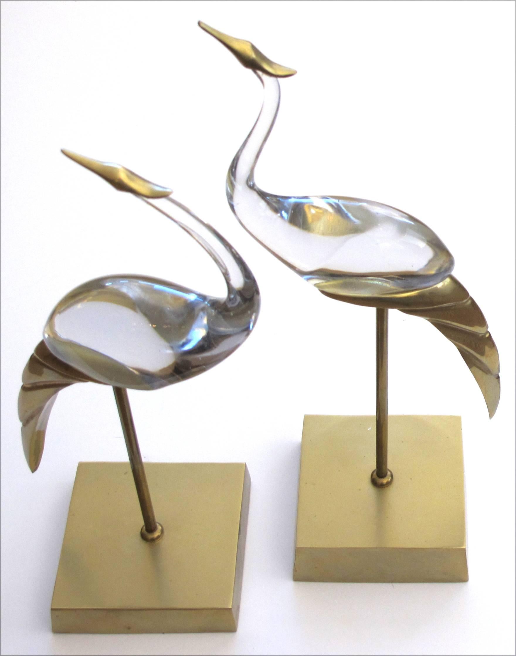 A shimmering and stylized pair of Italian Mid-Century brass and glass standing cranes by Luca Bojola; each elegantly poised bird with stylized bodies resting on brass plinths.