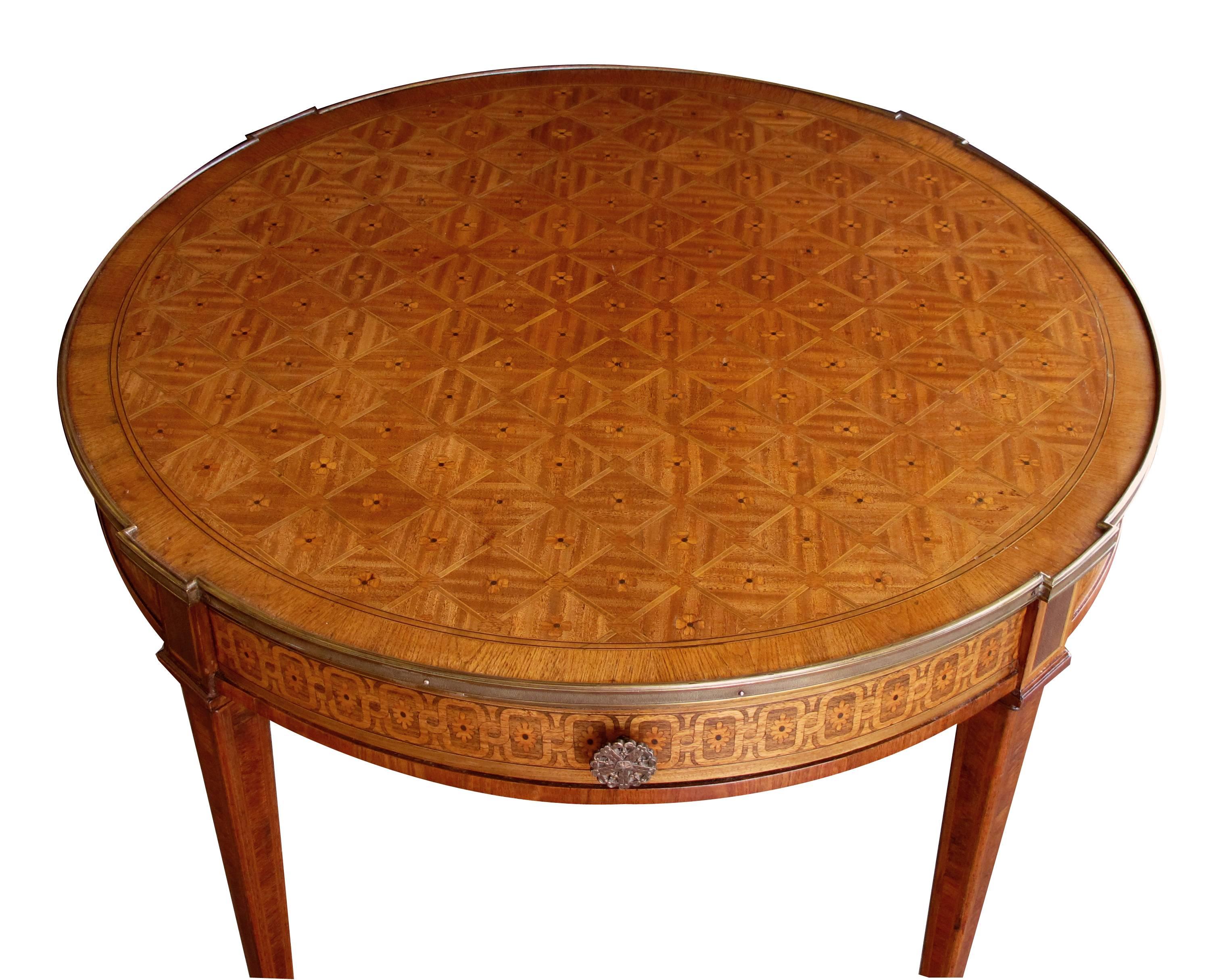 An elegant and good quality French Louis XVI style tiger mahogany and kingwood parquetry and marquetry inlaid circular bouillotte table; the circular top with diamond and floral inlay marquetry above an inlaid apron fitted with a single drawer;