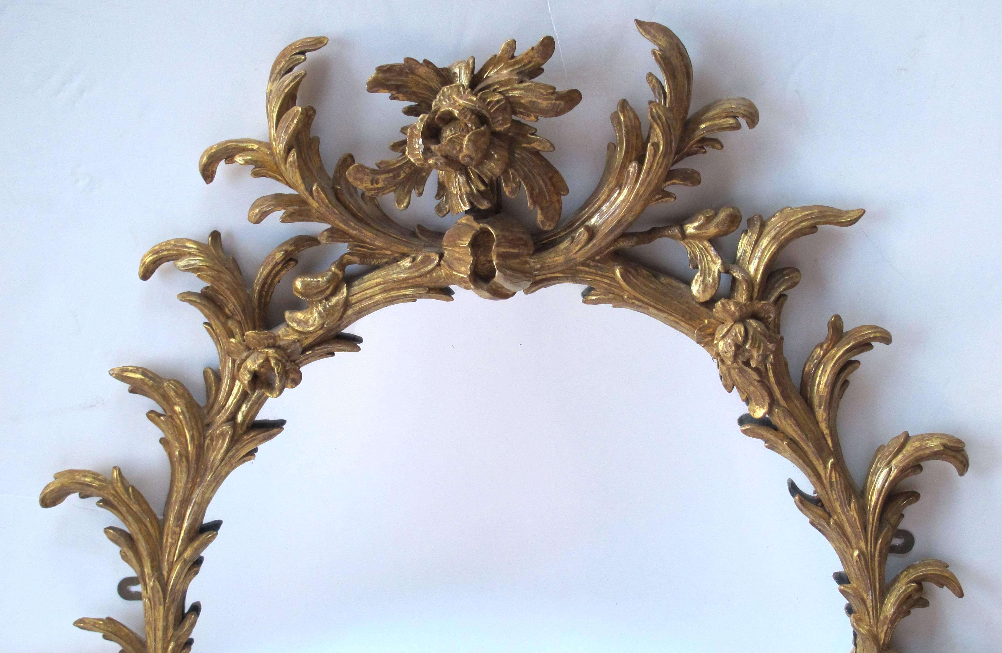 The well-carved and beautifully gilded oval mirror depicting lively acanthus leaves adorned with protruding flower heads.