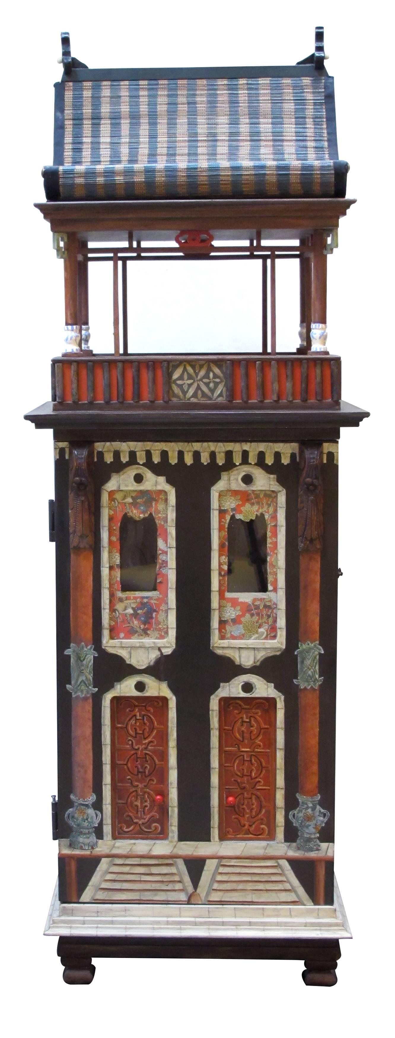 A rare and masterfully crafted wooden hand-painted dollhouse/cabinet of a whimsical Chinese palace by famed artisans Eric and Carole Lansdown; the charming and fanciful palace adorned with painted doors and glass windows; adorned on all sides with