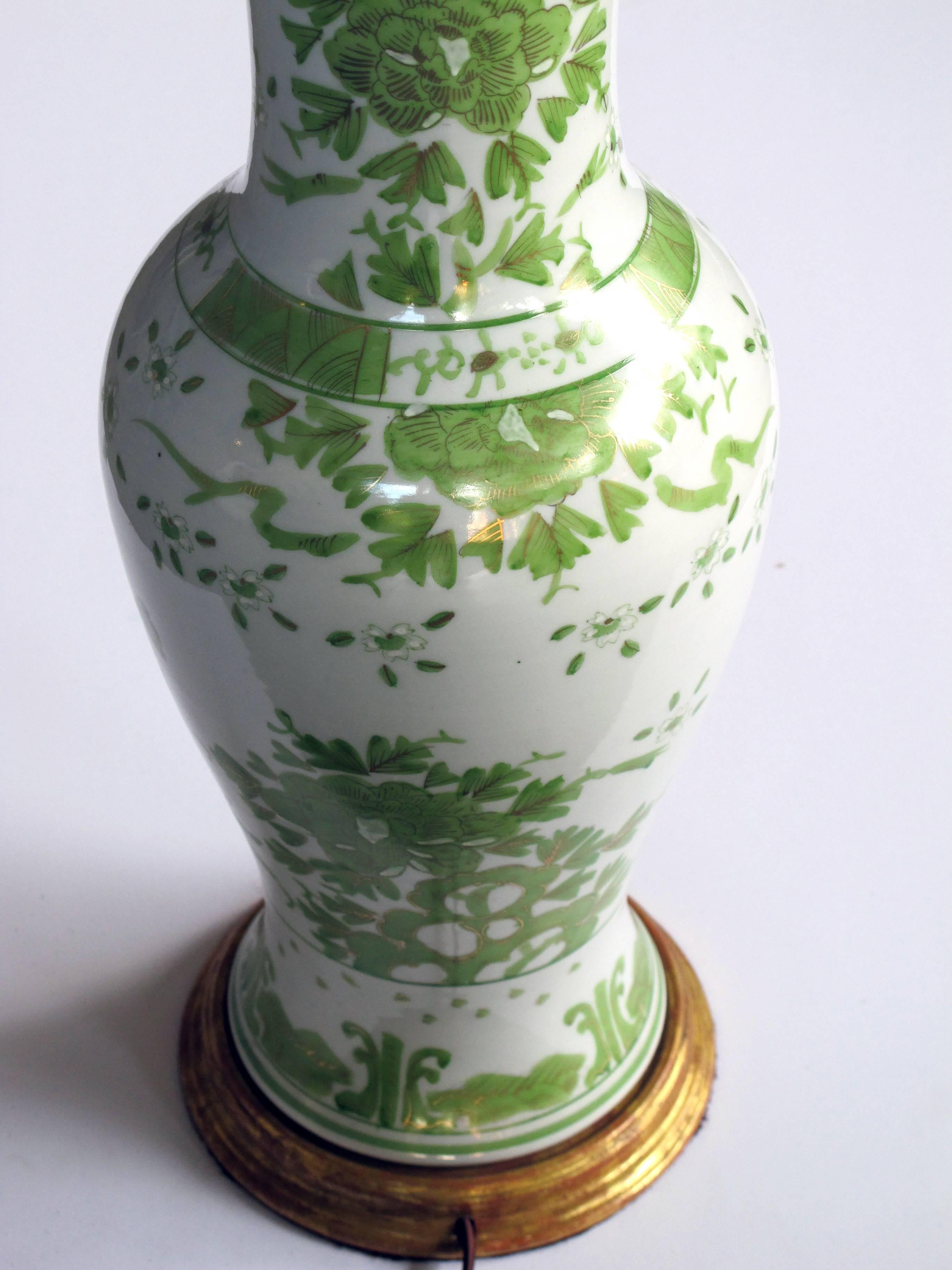 A finely painted pair of Japanese, 1960s baluster-form porcelain lamps with apple green and gilt decoration; each large-scale lamp with Fine decoration resting on a giltwood base; by JL Porcelain Co., Japan.