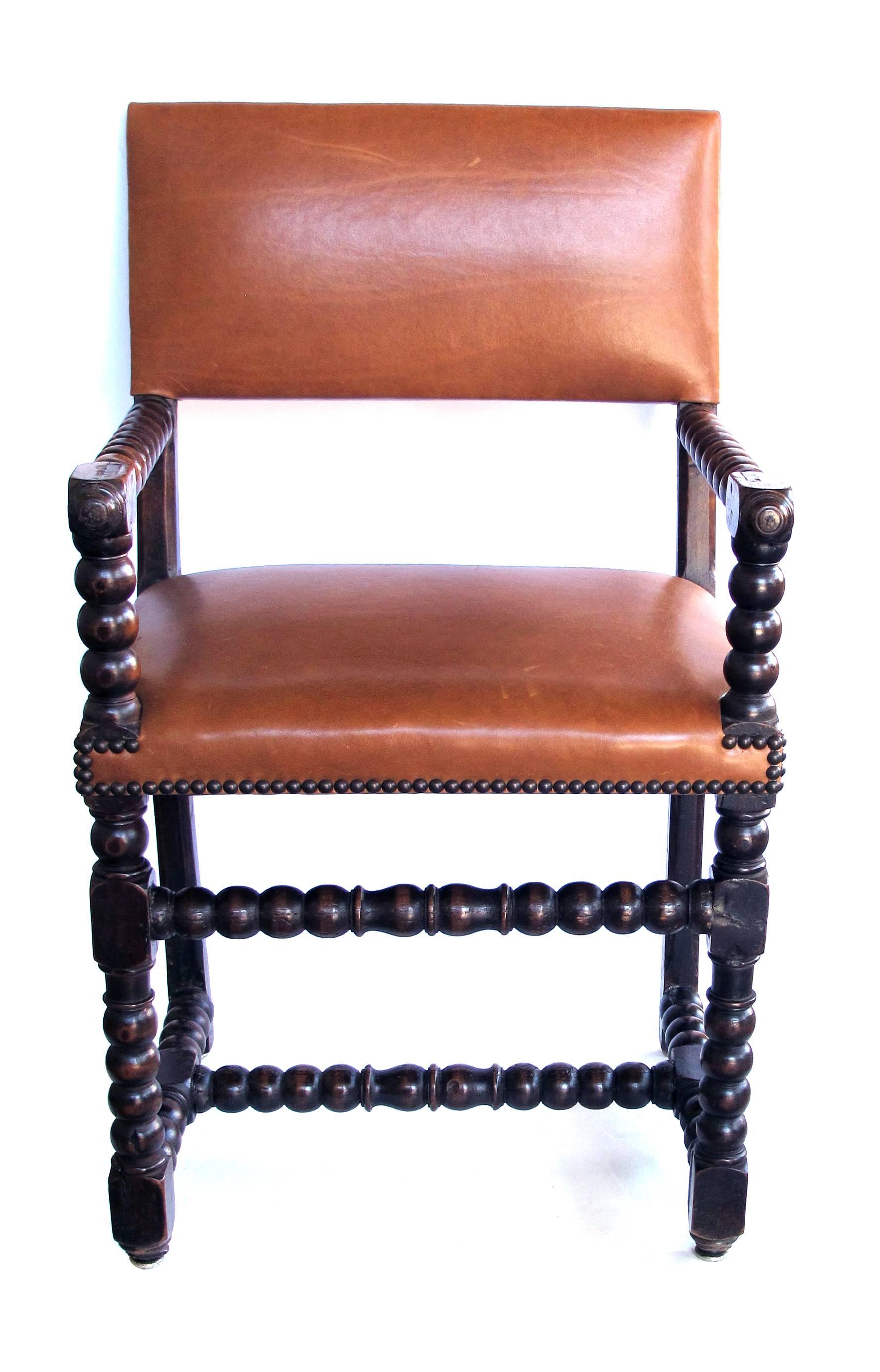 A handsome English Baroque style carved walnut bobbin chair with leather upholstery.