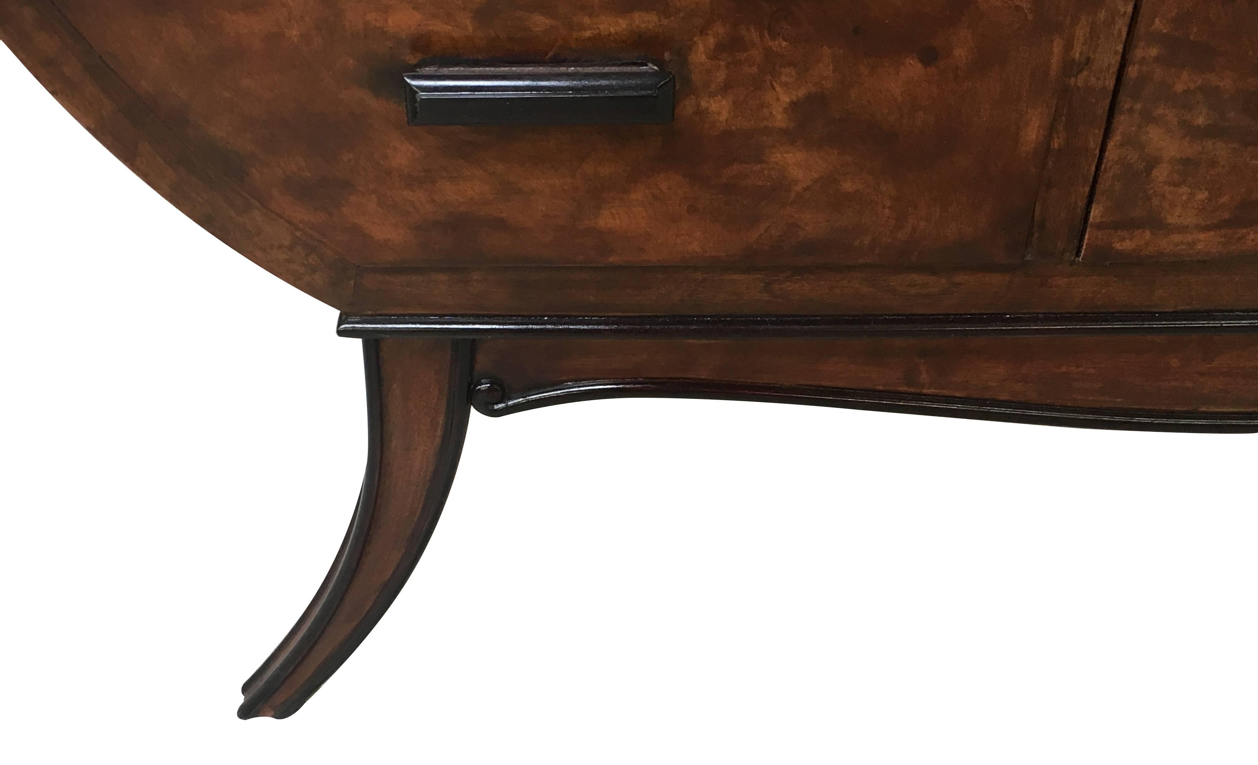 The voluptuous form with tapering curved sides raised on elegantly splayed supports all fitted with 9 short drawers; the whole in a richly-figured madrone burlwood veneer