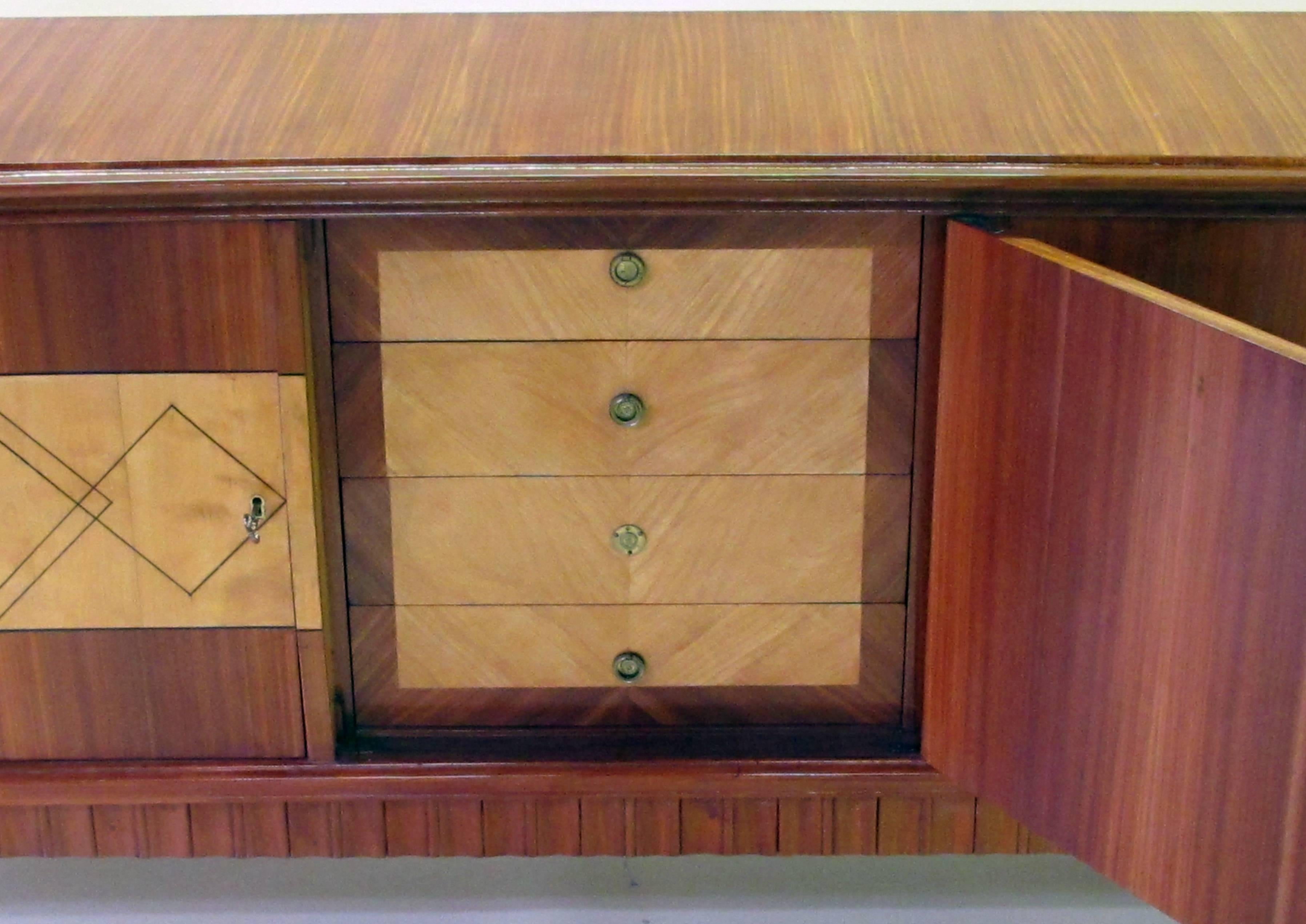 An exceptionally long and superb quality Italian midcentury five-door walnut and sycamore incurved sideboard in the manner of Paolo Buffa; have curved front with five inlaid doors, all raised on turned and flared feet with brass terminals; the
