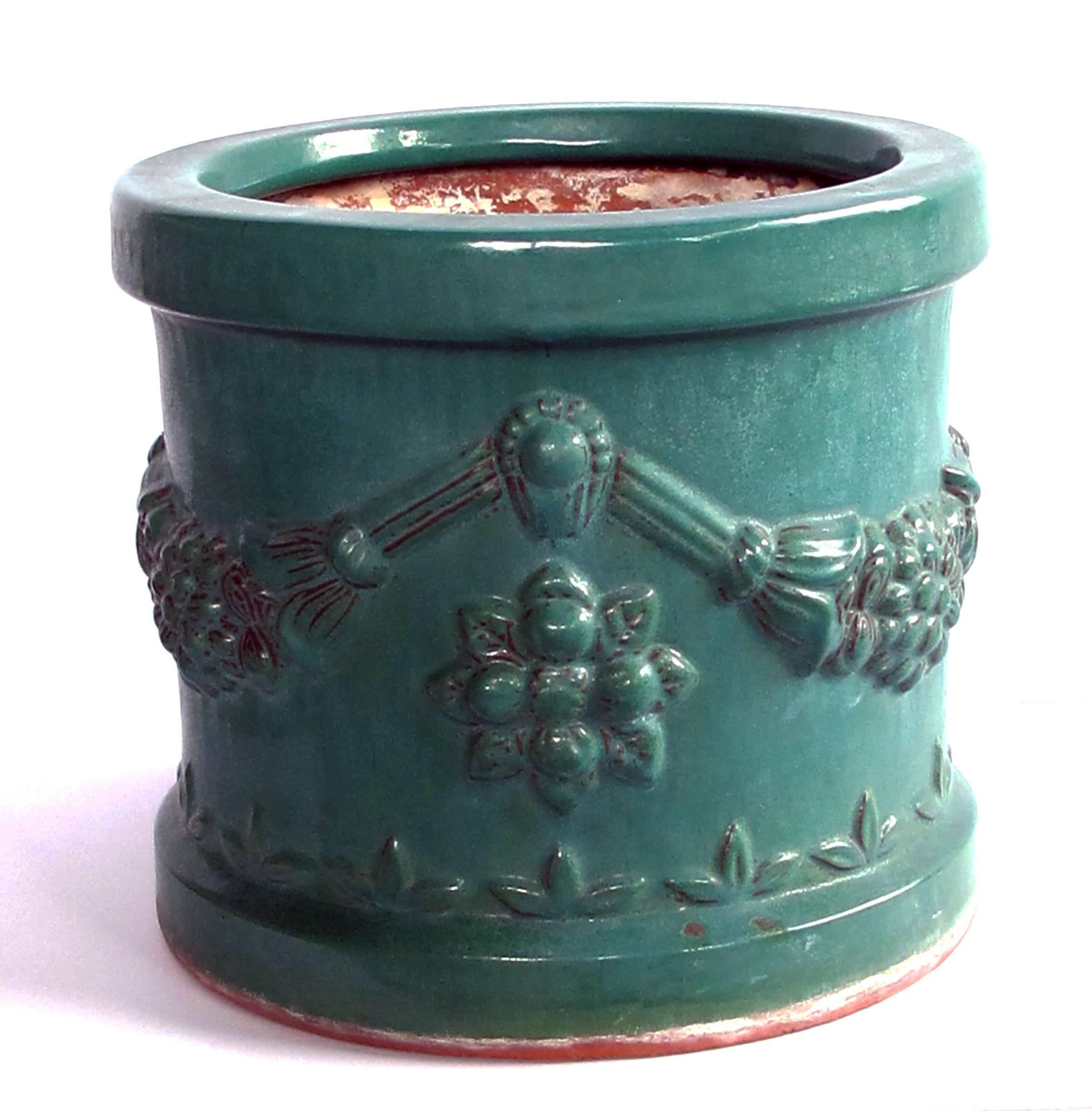 A robust pair of Malaysian teal-glazed terracotta planters with raised floral garland; each of cylindrical form adorned with floral festoons; fine overall craquelure to glaze; perfect for orchids.