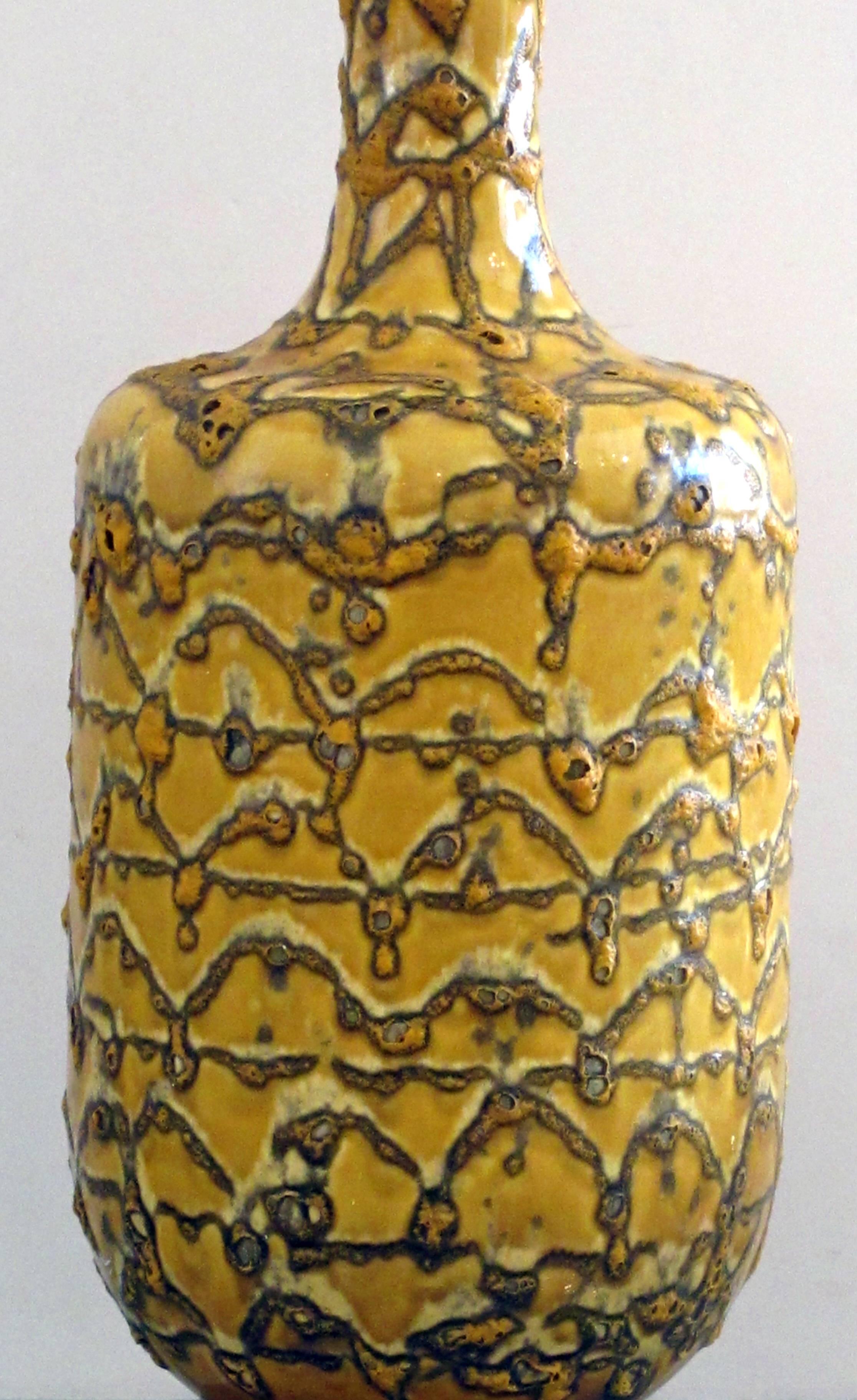A mod American 1960s mustard crater-glazed bottle-form lamp; the large bottle-form lamp with long neck and tapering body all in a crater glaze.