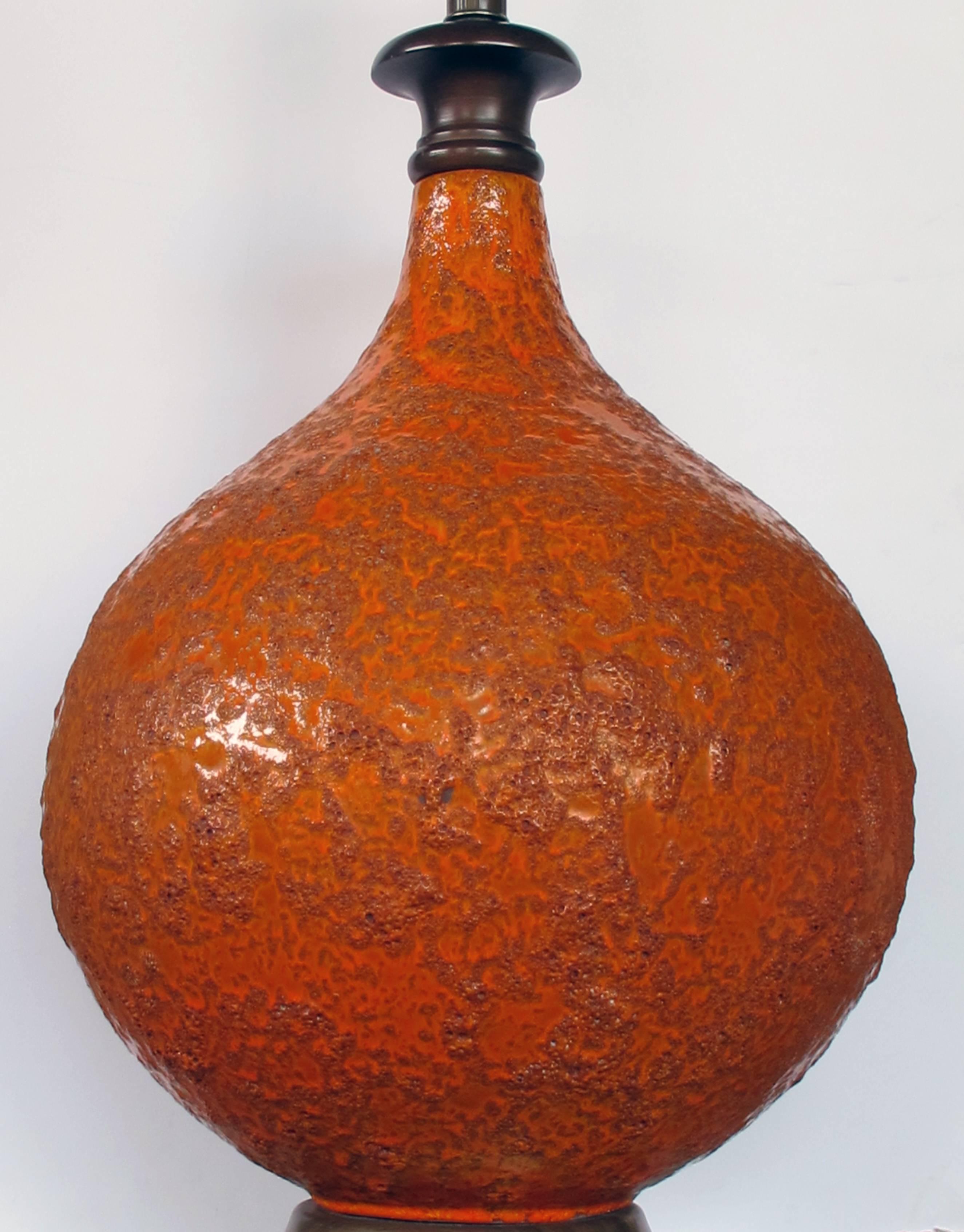 La grande lampe en forme de bouteille est recouverte d'une glaçure de cratère orange brûlée richement texturée.