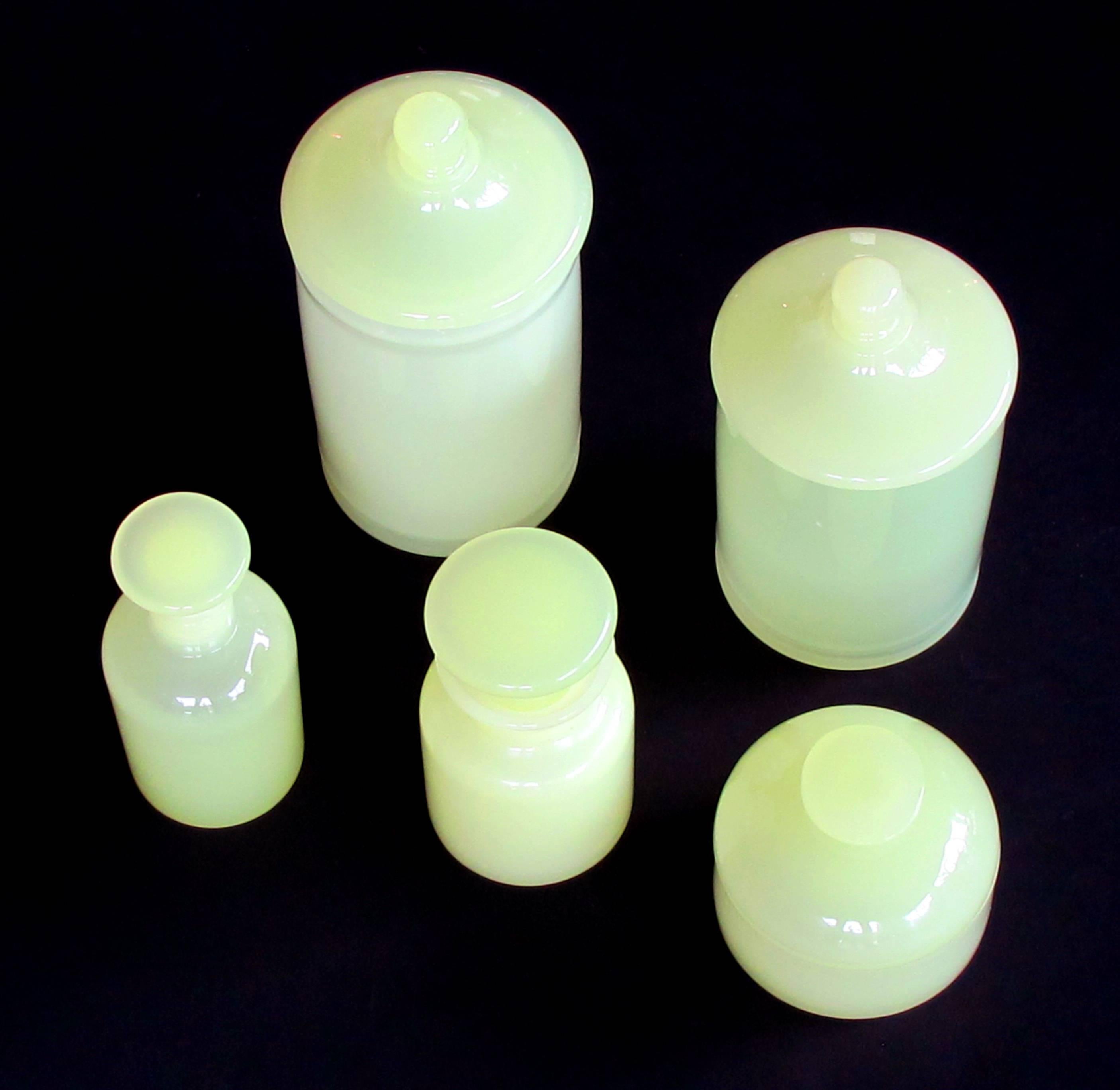 A luminous set of Murano Cenedese mid-century vessels of pale chartreuse opaline glass; consisting of 2 lidded jars, 2 scent bottles and a covered bowl; all in a translucent chartreuse glass; labeled 'Cenedese Glass, Murano, Made in Italy'